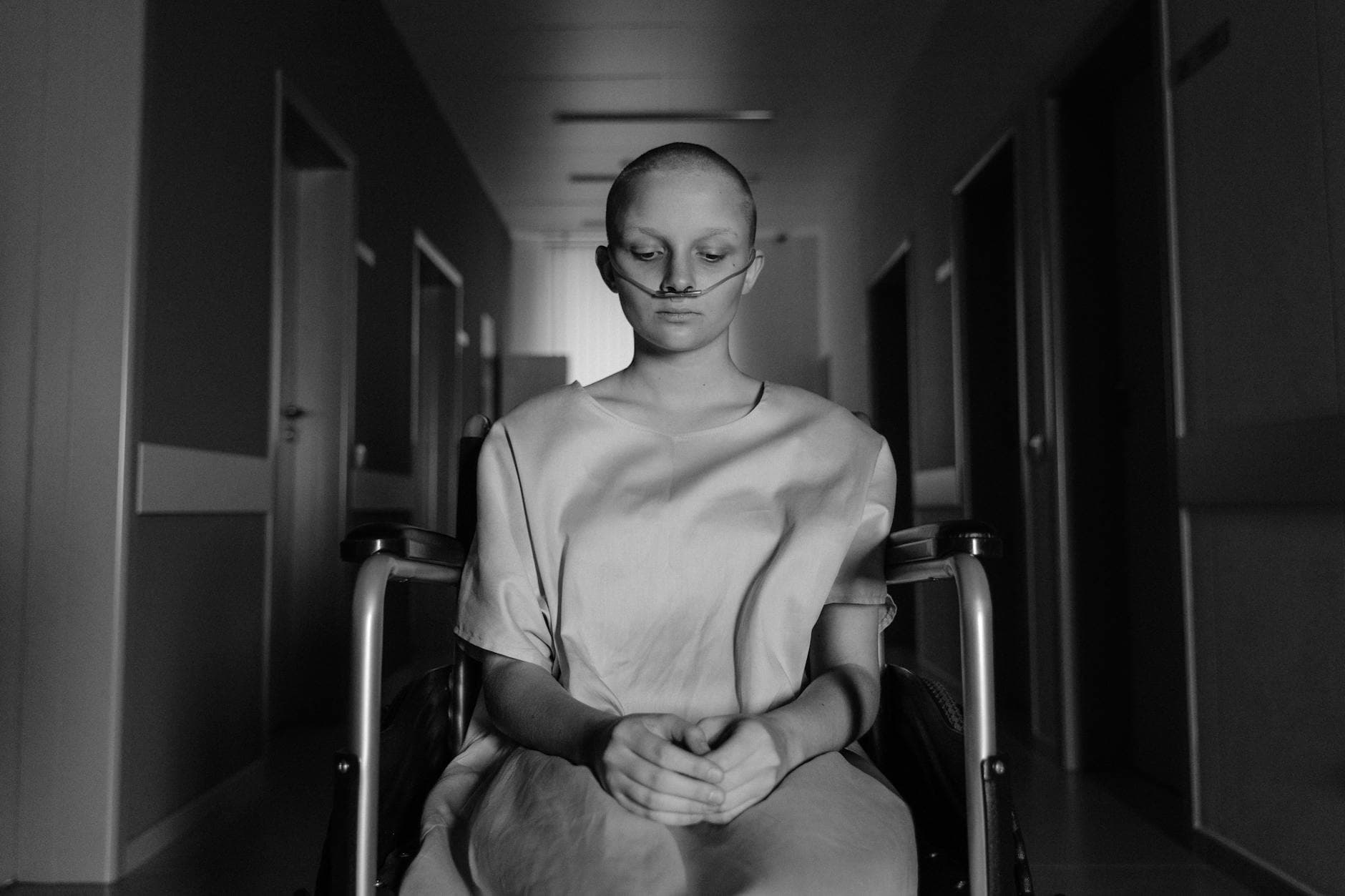 A woman in a wheelchair, deep in thought, in a hospital corridor. - latest postpartum depression treatments