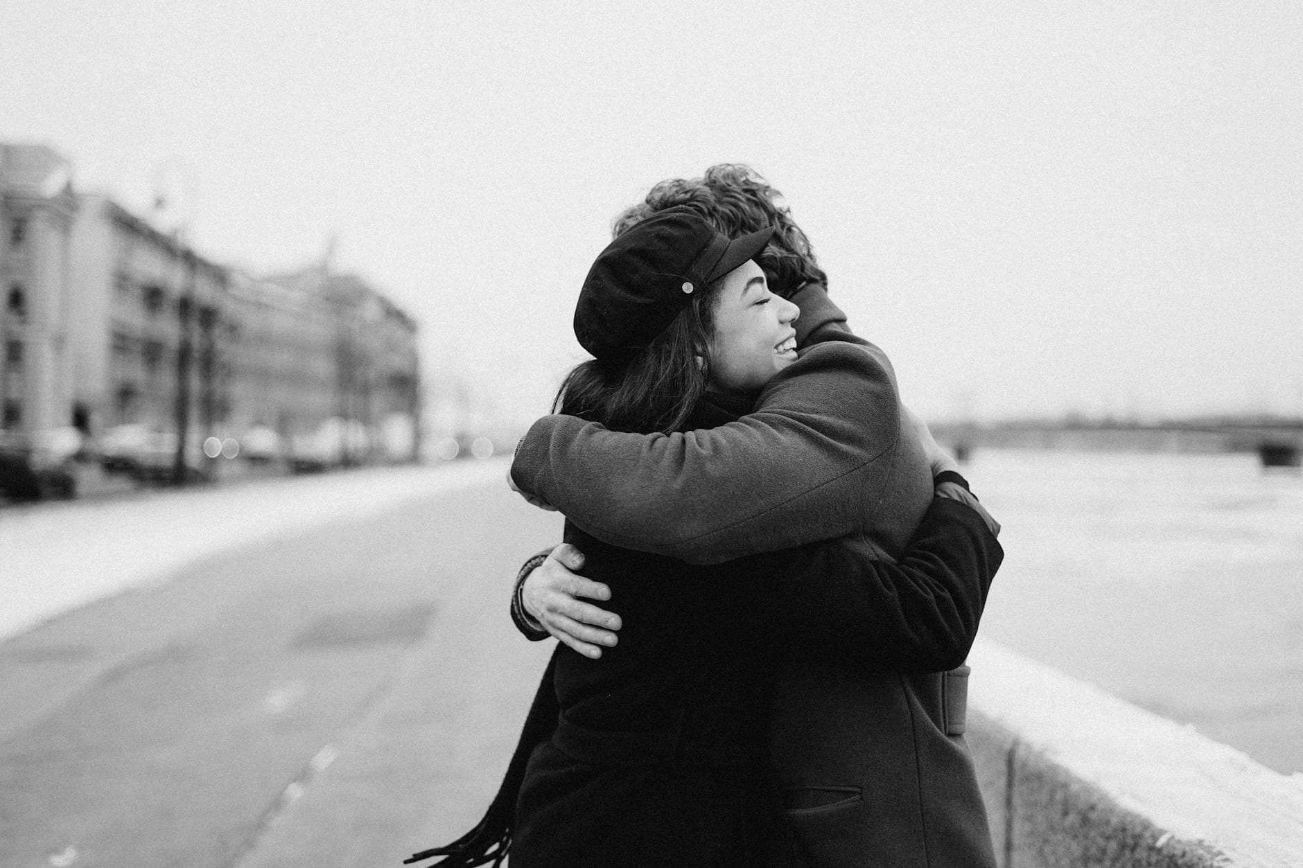 Black and white scene of a couple hugging by the waterfront in winter, capturing love and happiness. - post valentine's relationship expectations