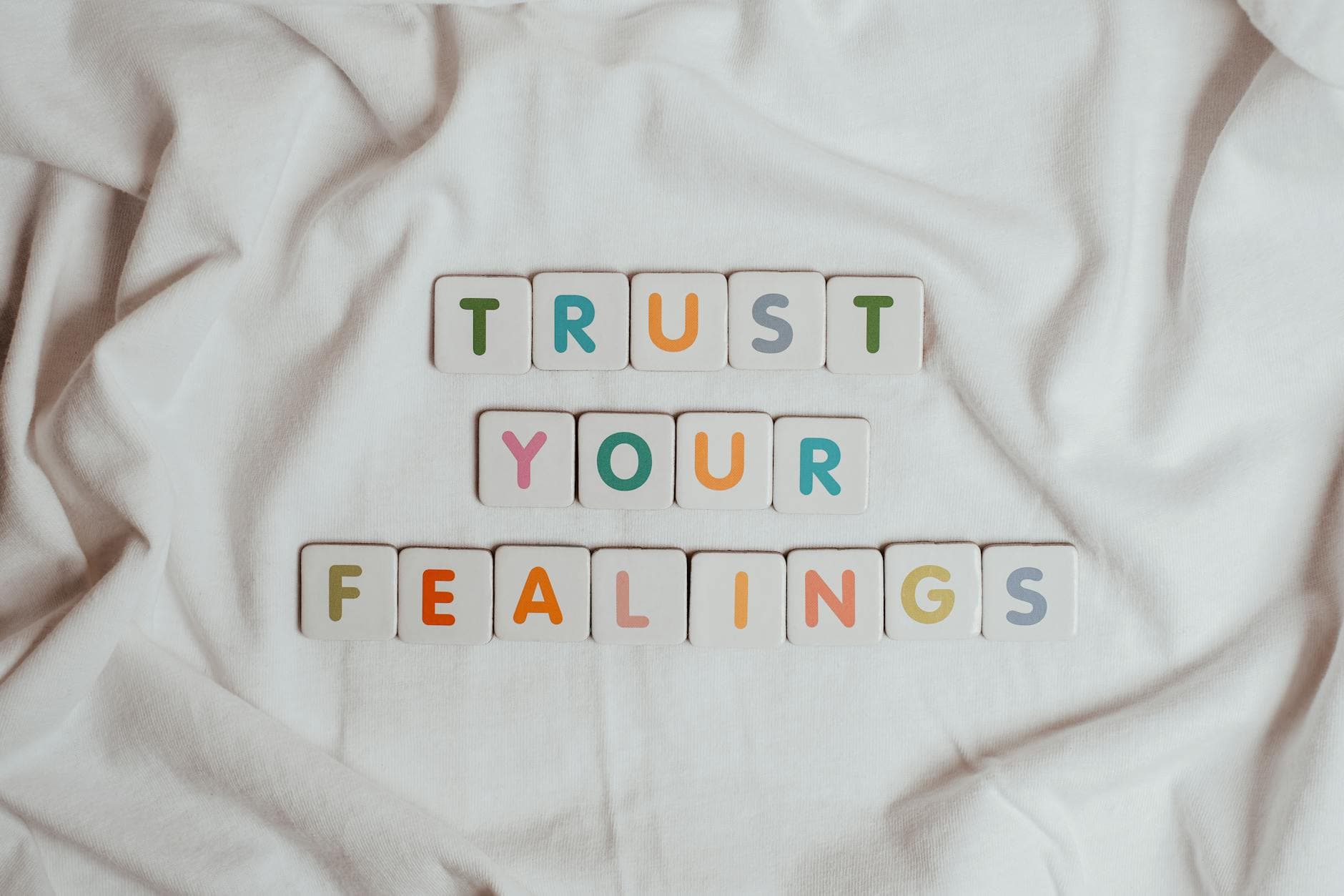Colorful tiles spell out 'Trust your feelings' on a fabric background. - rebuilding trust quotes