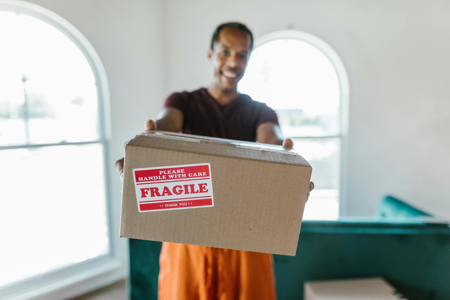 A person holding a cardboard box labeled fragile, signifying careful handling during a move. - couple communication tips