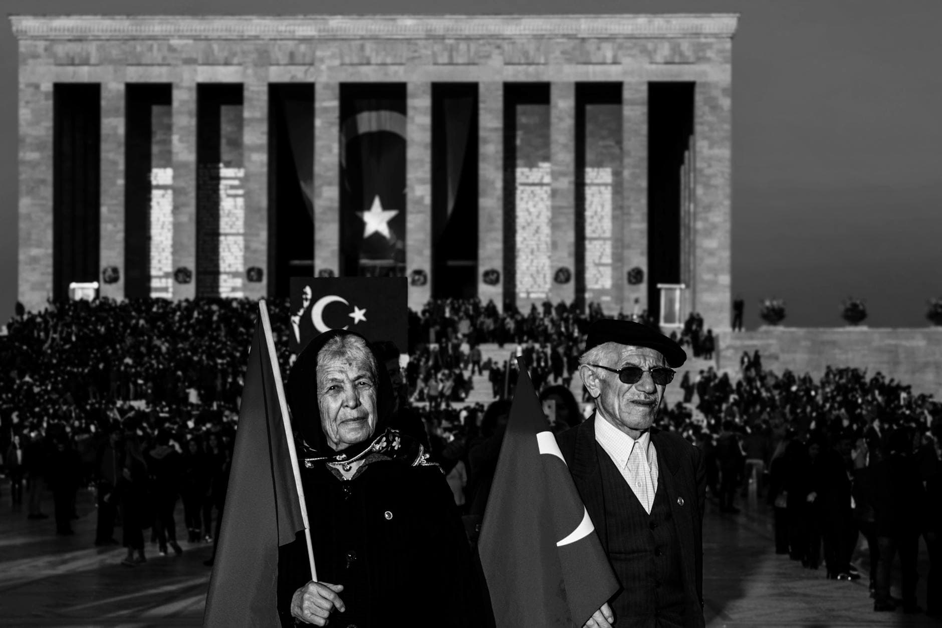 Turkish veterans holding flags at Anıtkabir during a commemorative event in black and white. - dating red flags