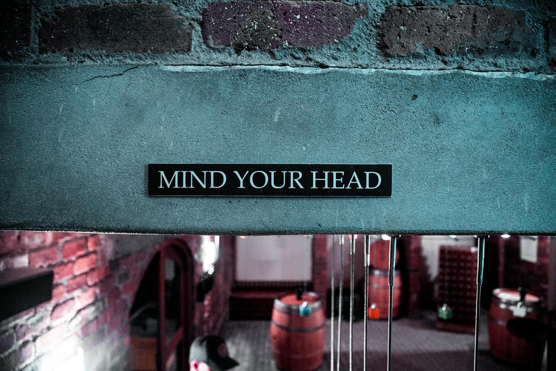 A 'Mind Your Head' sign in a rustic brick barrel cellar setting, creating a safety awareness ambiance. - declutter your mind