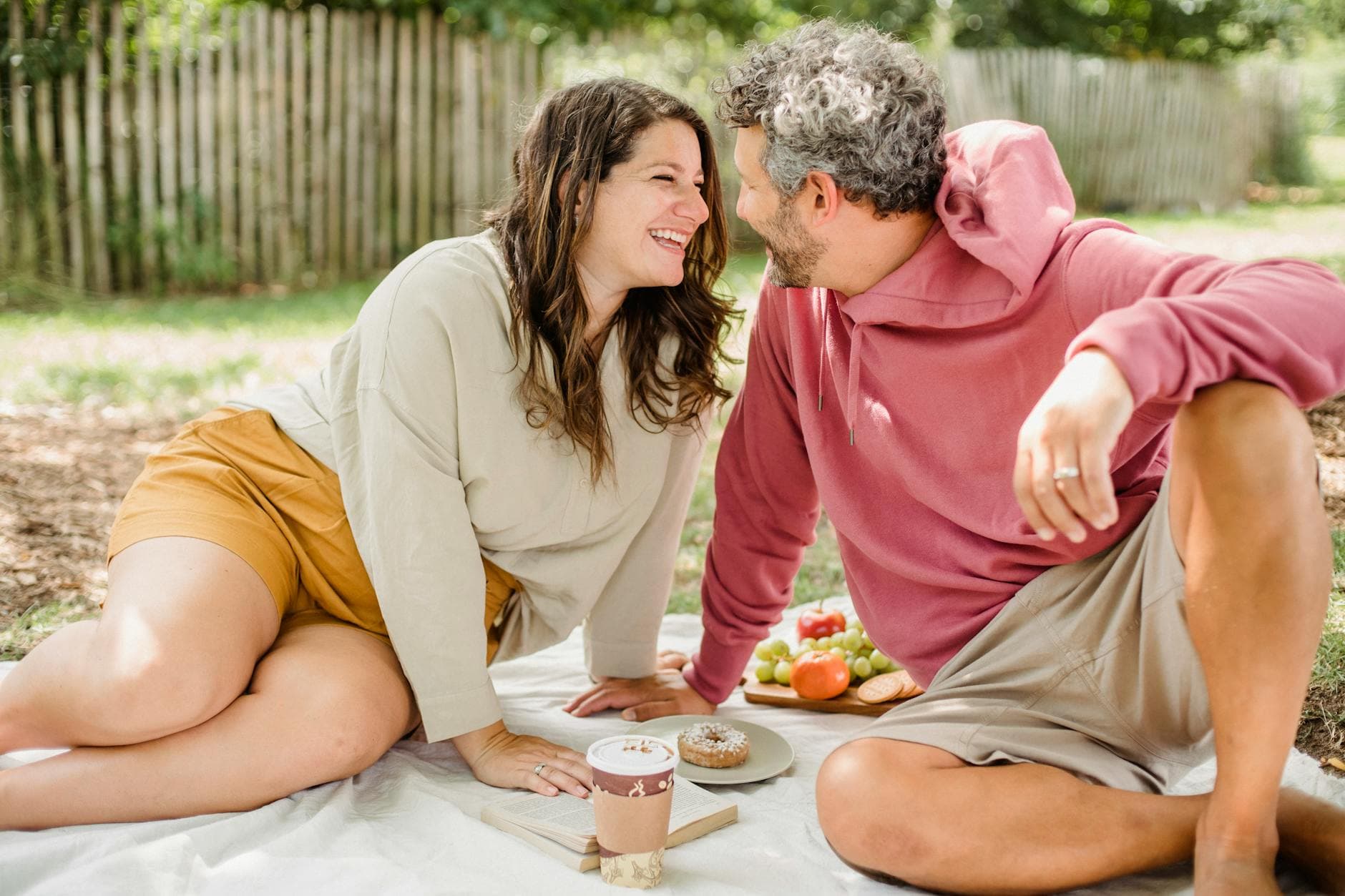 A loving couple enjoys a sunny picnic with coffee, fruits, and pastries outdoors. - healthy relationship signs
