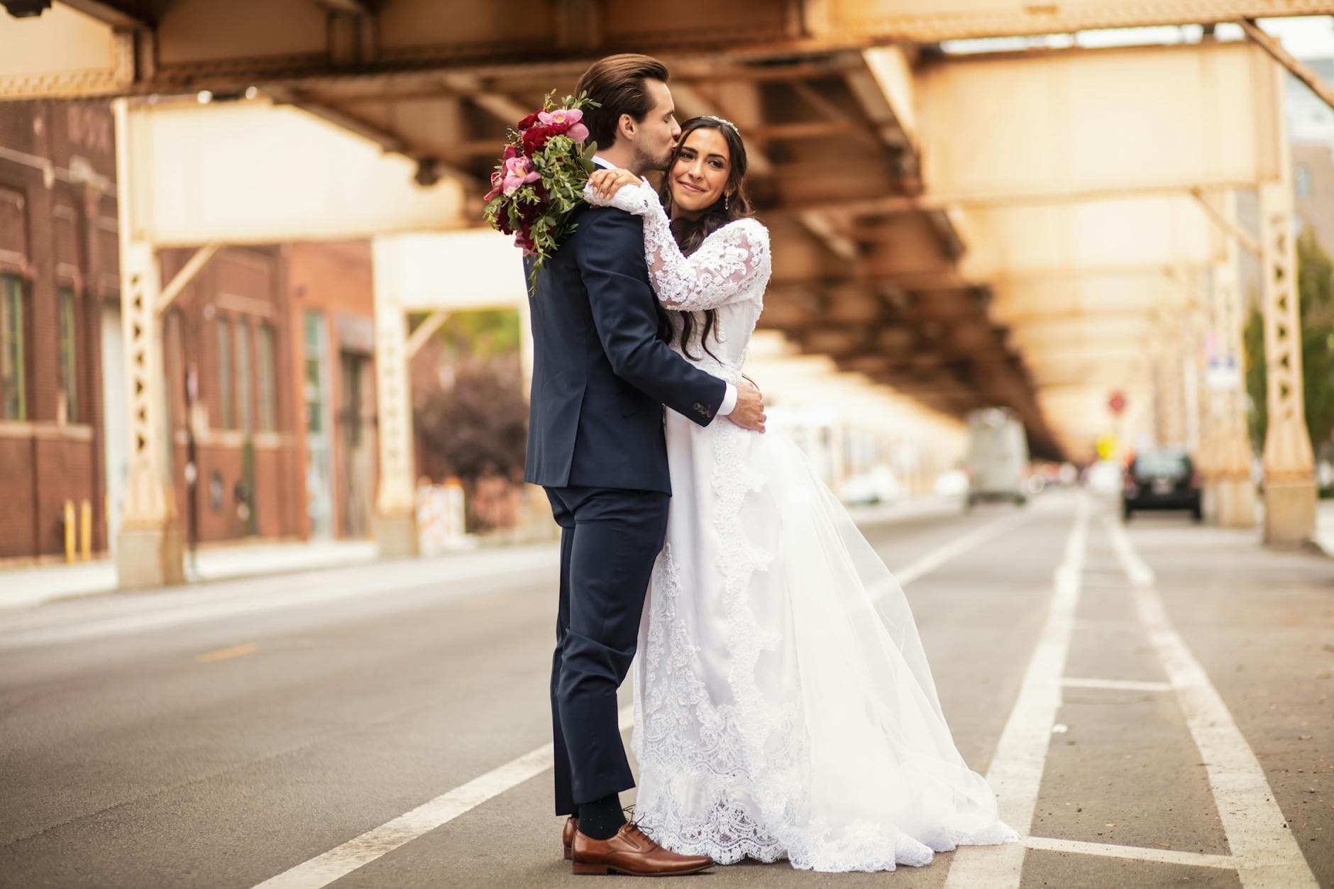 A romantic wedding moment captured under a historic bridge in the city featuring a joyful bride and groom. - marriage advice bride