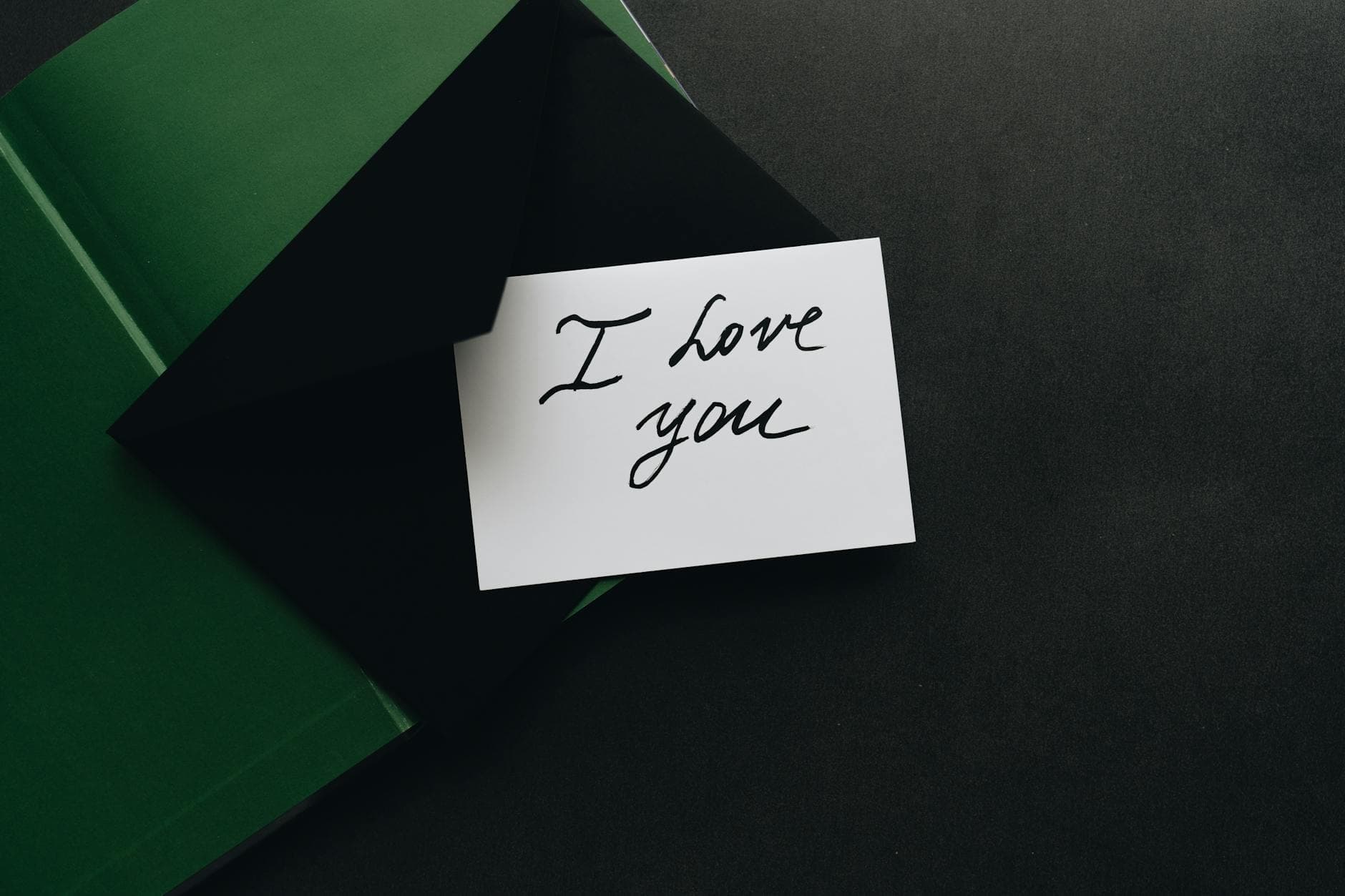 A stylish 'I Love You' note inside a dark green envelope on a flat surface. - marriage advice cards