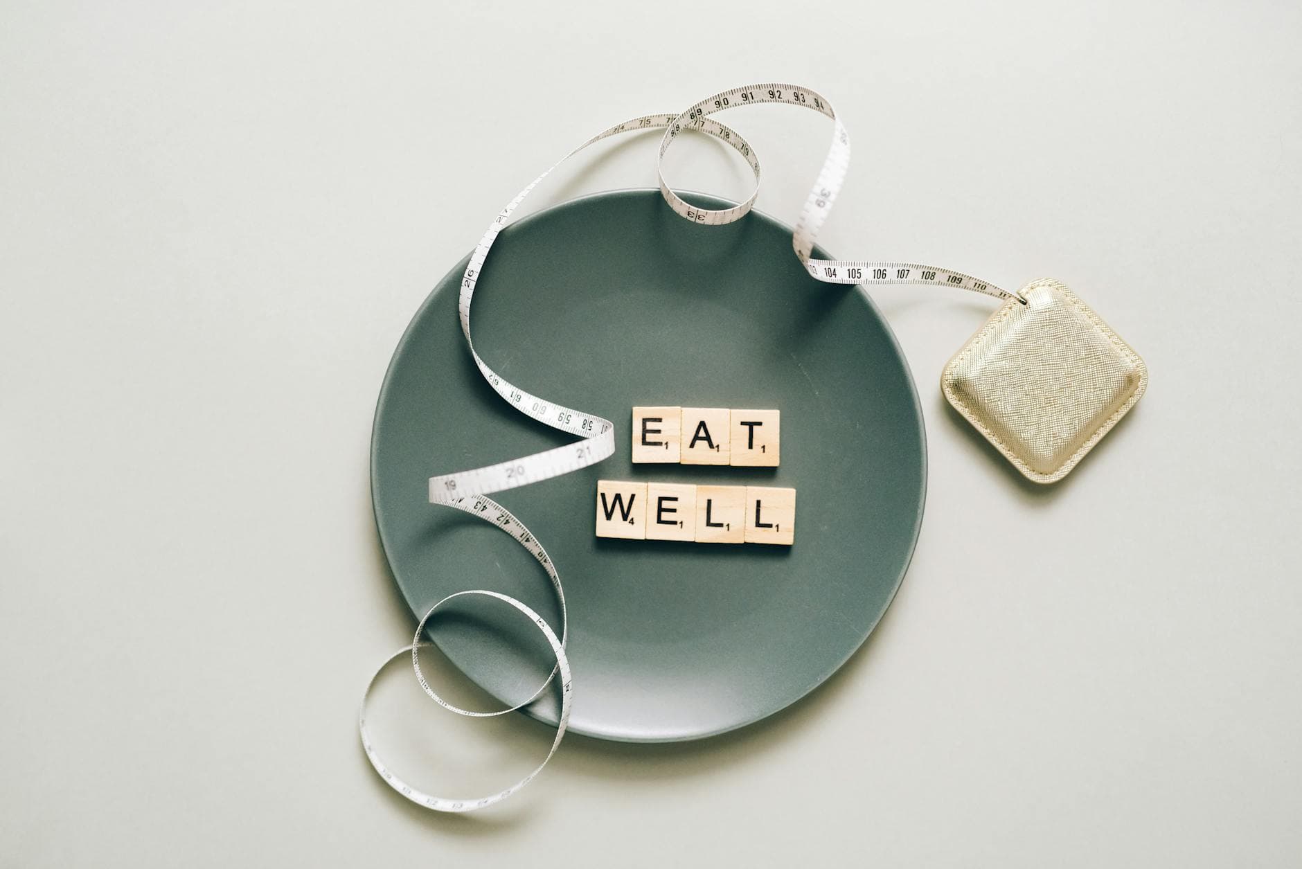 Flat lay of scrabble tiles spelling 'eat well' on a plate with a tape measure, promoting healthy eating. - mindful eating winter wellness