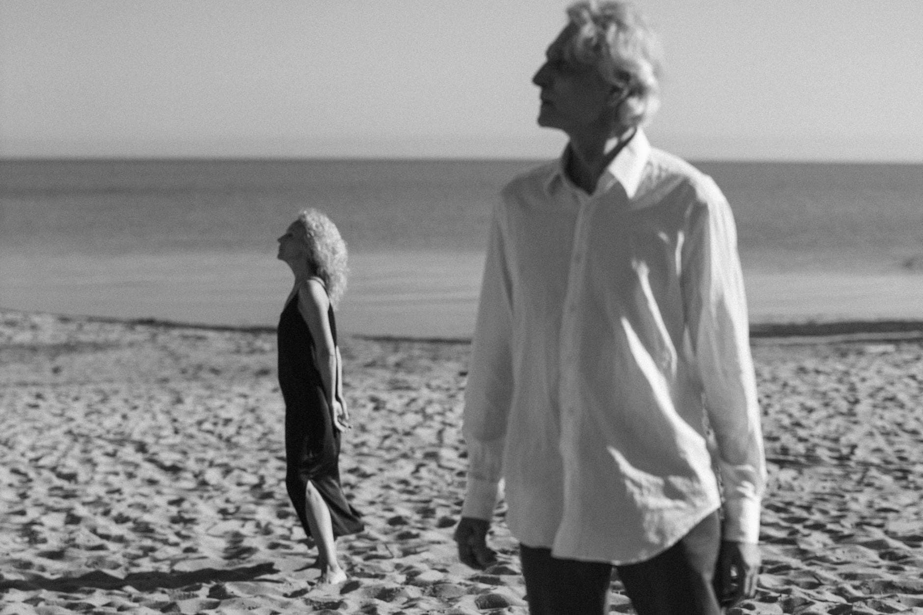 An elderly couple walking on a serene beach, captured in monochrome, embracing tranquility. - outdoor play benefits