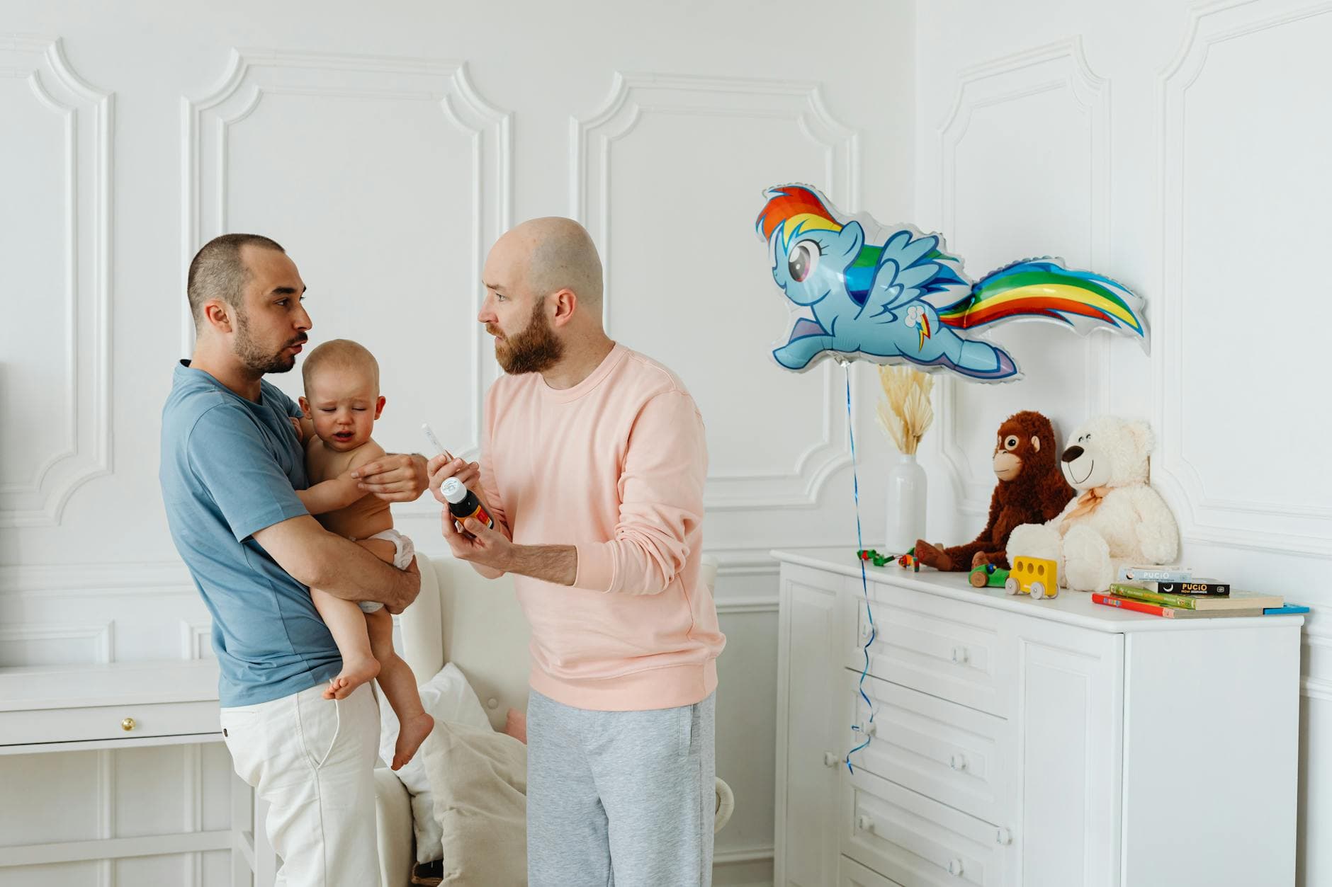 A same-sex couple taking care of their baby in a beautifully decorated room, surrounded by toys. - parent child communication