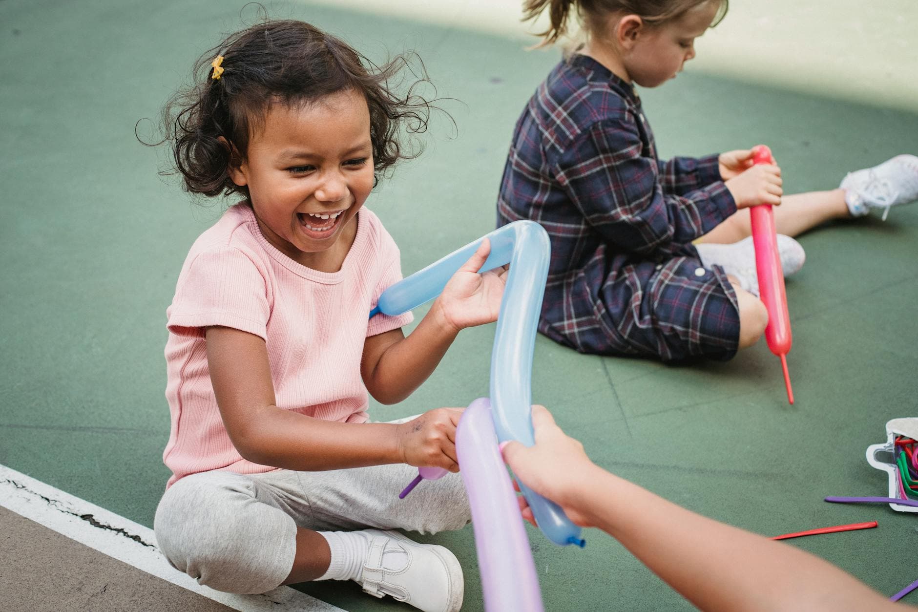 Children playing with colorful balloon animals on a playground, smiling and joyful. - preschool outdoor learning
