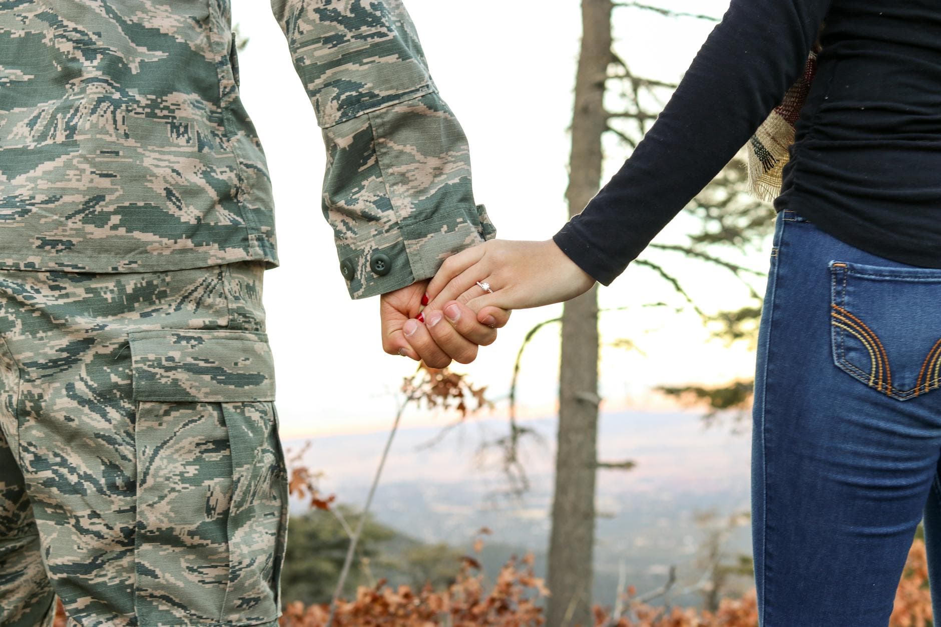 A soldier in uniform holding hands with a woman showing her engagement ring outdoors. - rekindle marriage intimacy
