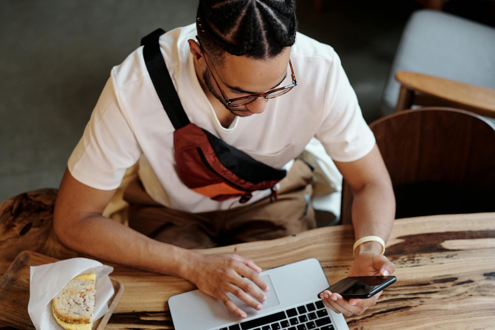 A focused freelancer uses a laptop and smartphone while sitting at a cafe table indoors. - screen time balance