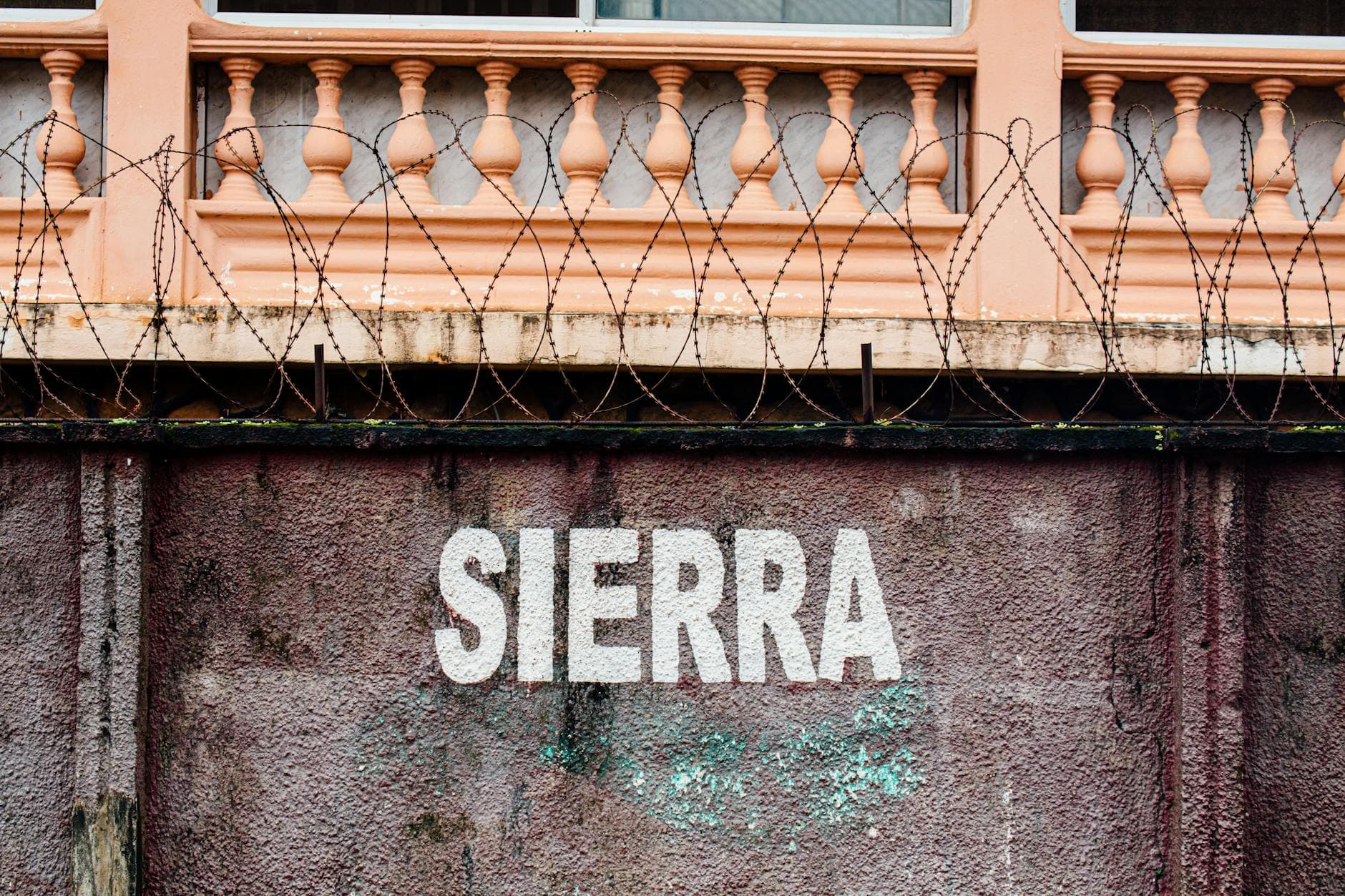 A rustic wall featuring a baluster, barbed wire, and a bold SIERRA sign. - setting boundaries after isolation