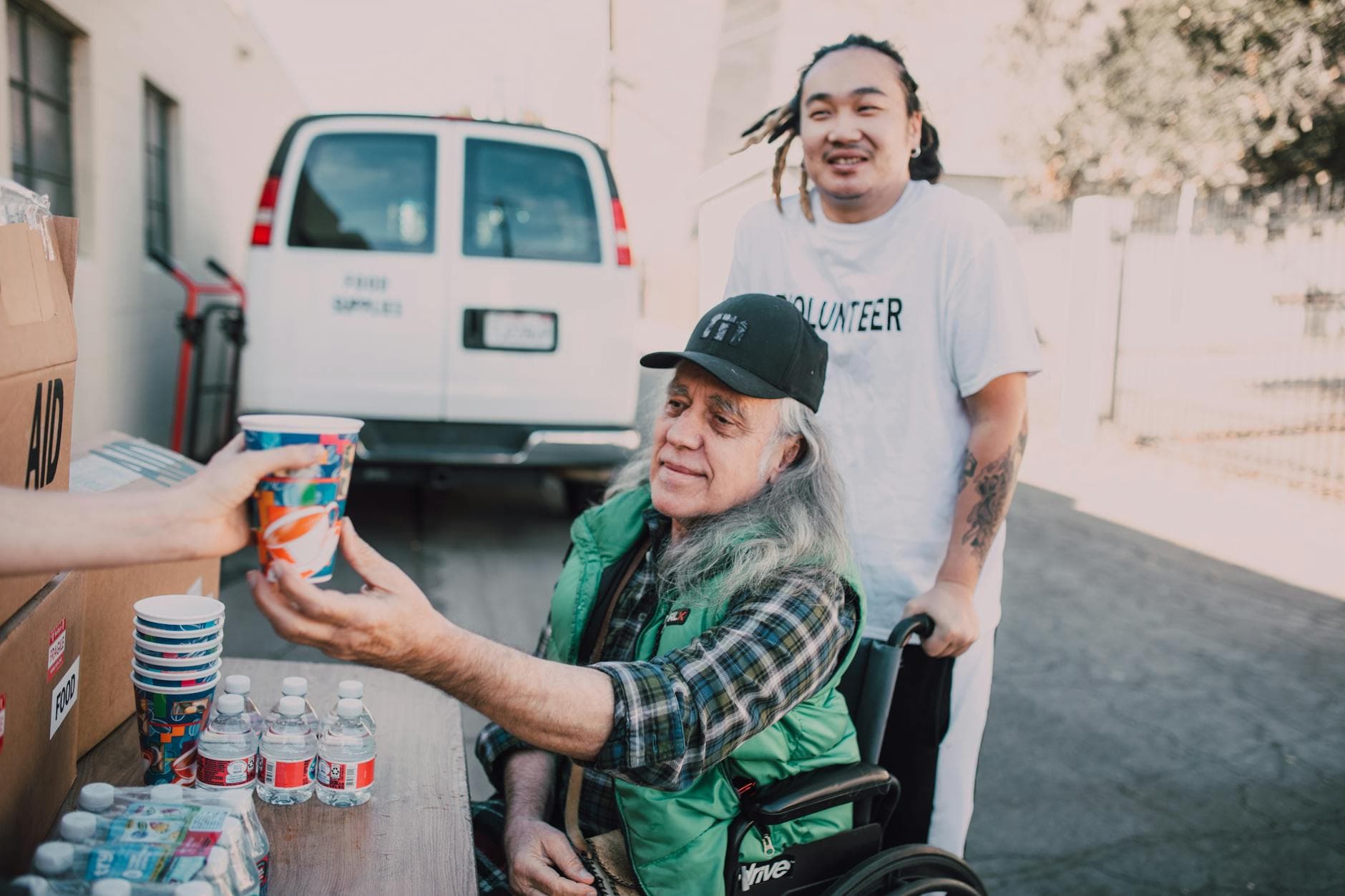 A volunteer assists an elderly man in a wheelchair receiving aid outdoors. - sexless marriage help