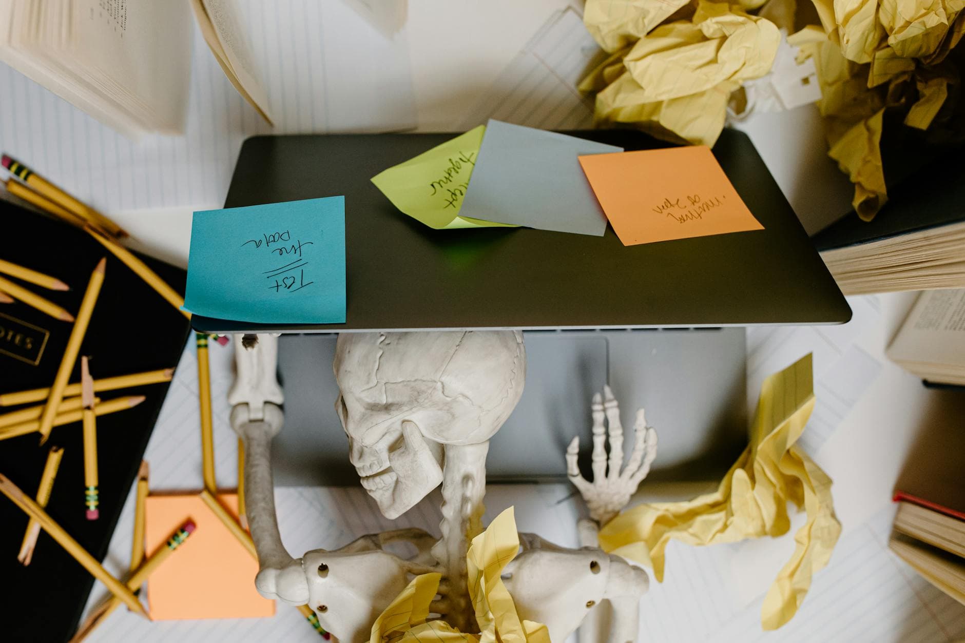 A striking visual of a skeleton at a laptop surrounded by notes and paper, symbolizing work burnout. - spring anxiety management