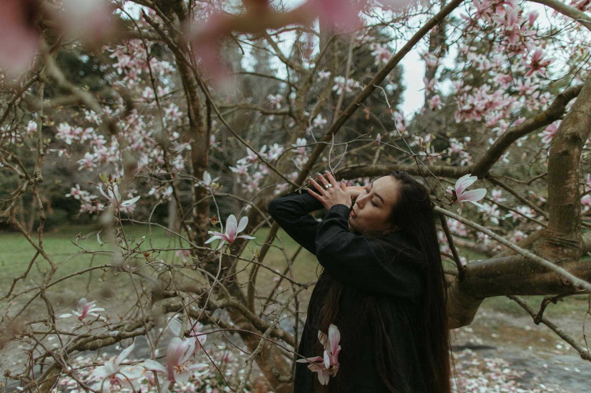A peaceful moment of a woman embracing nature surrounded by blossoming magnolias in spring. - spring melancholy therapy