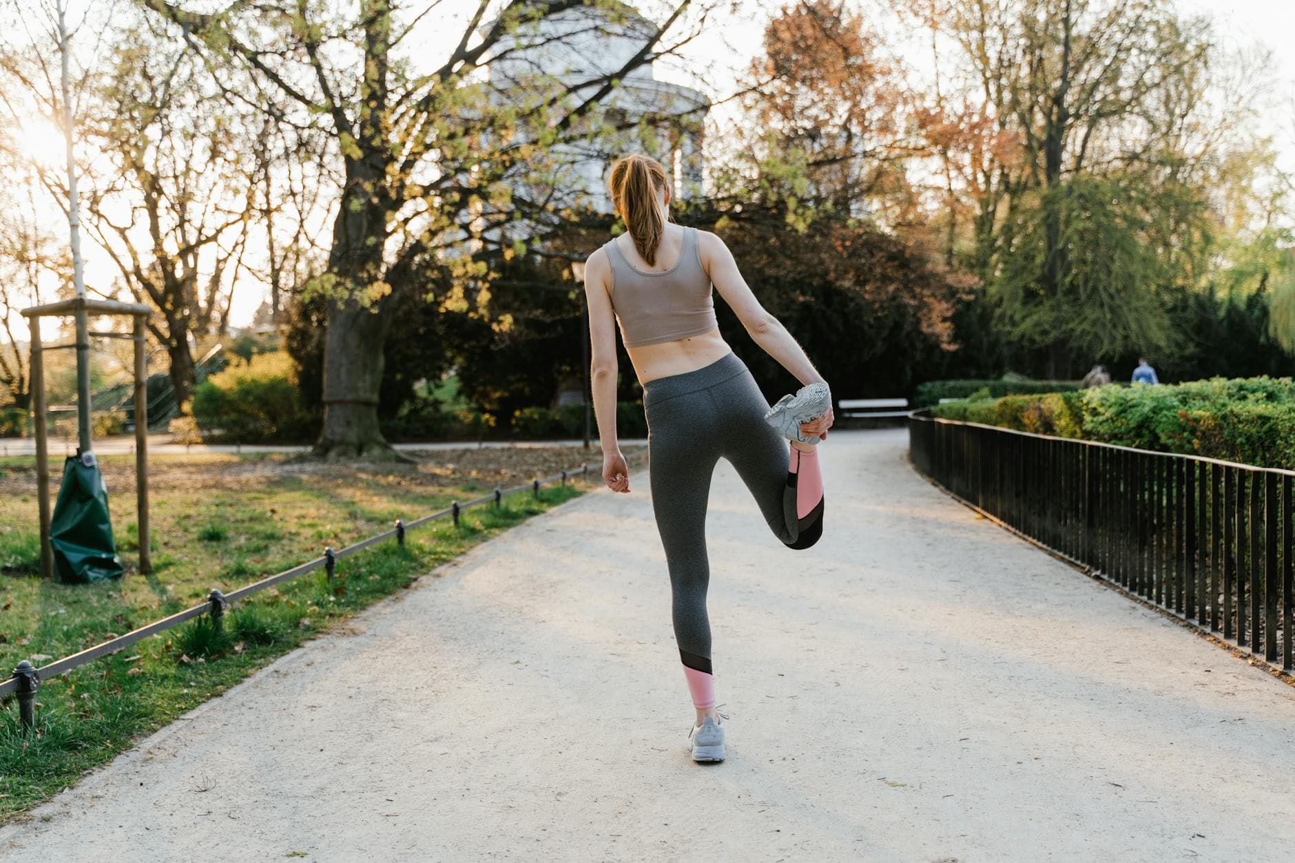 A woman performs a stretching exercise in a park setting, showcasing fitness and a healthy lifestyle. - spring outdoor activities mental health