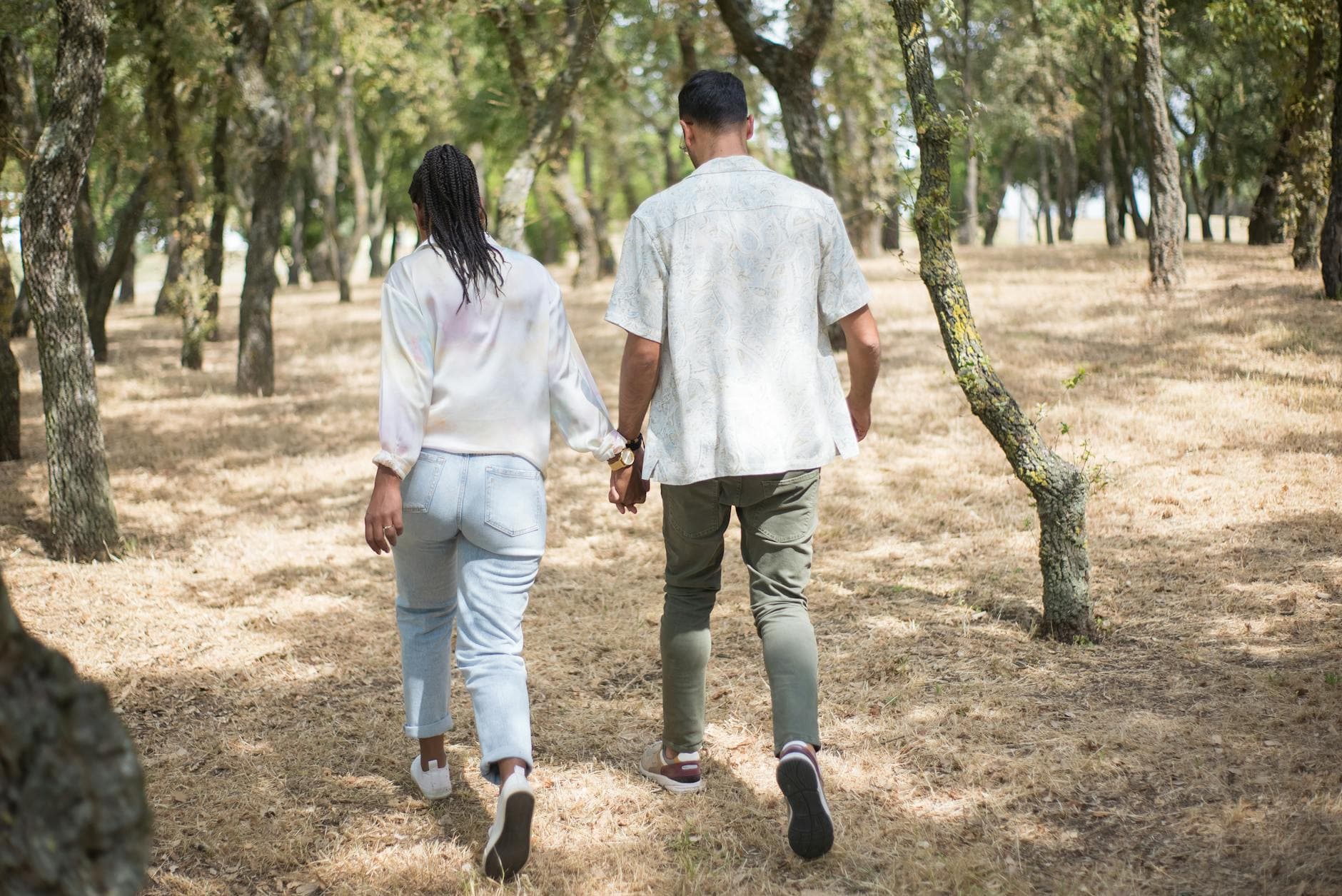 A loving couple holding hands while strolling in a sunlit forest in Portugal. - spring relationship reset