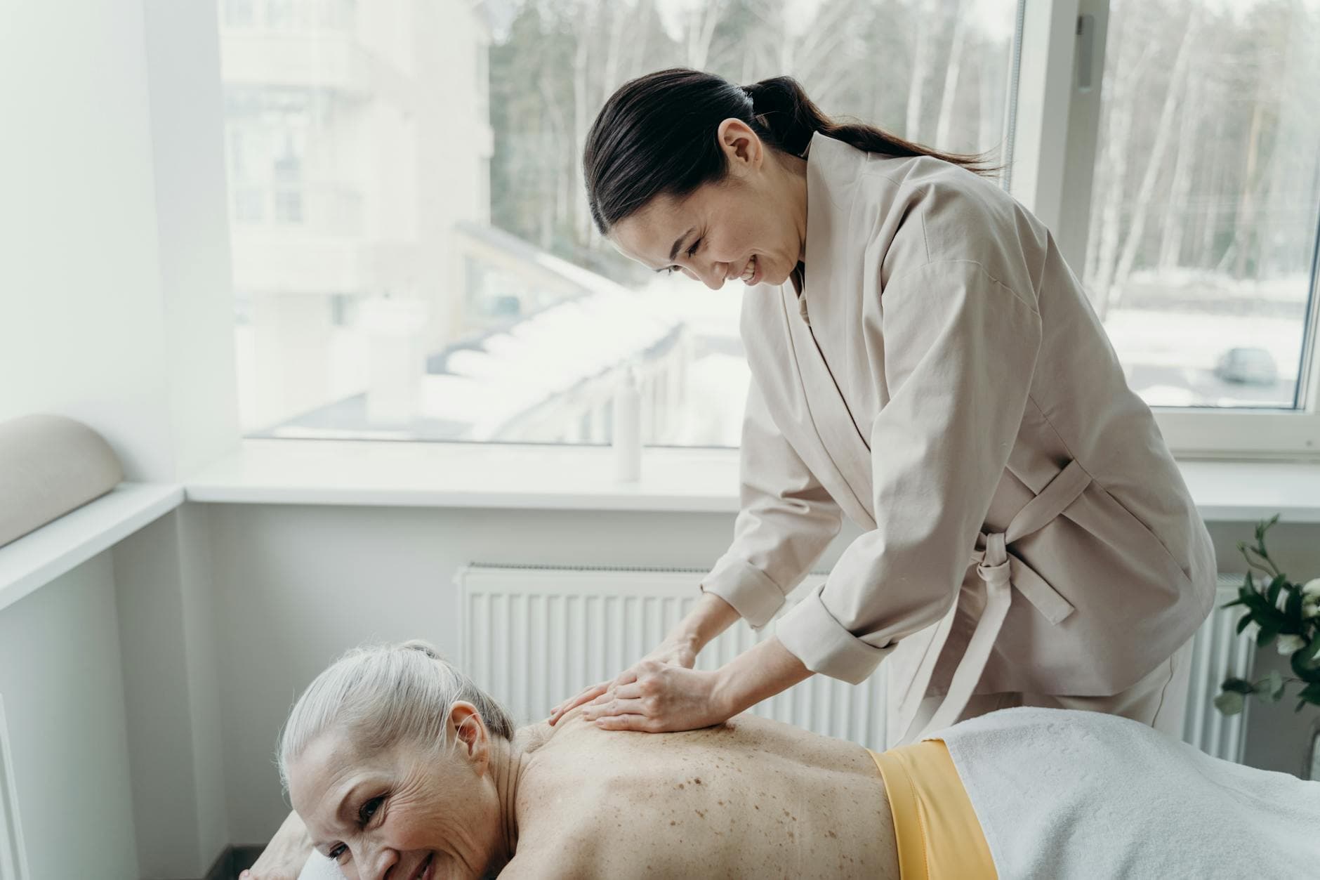 An elderly woman enjoys a soothing back massage in a bright, serene spa setting. - virtual therapy benefits