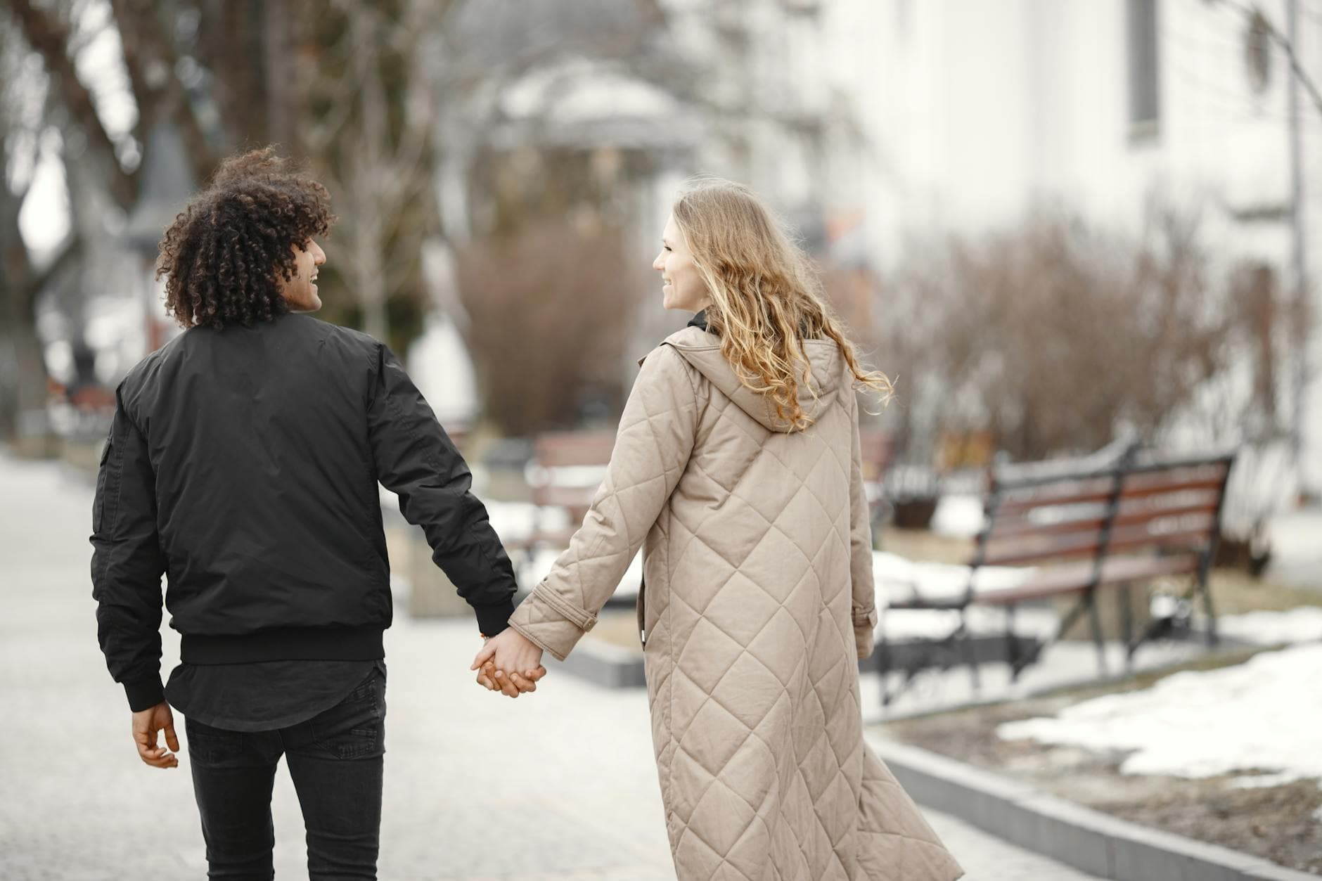A happy couple walking hand in hand during a winter day, wearing cozy coats outdoors. - winter relationship activities