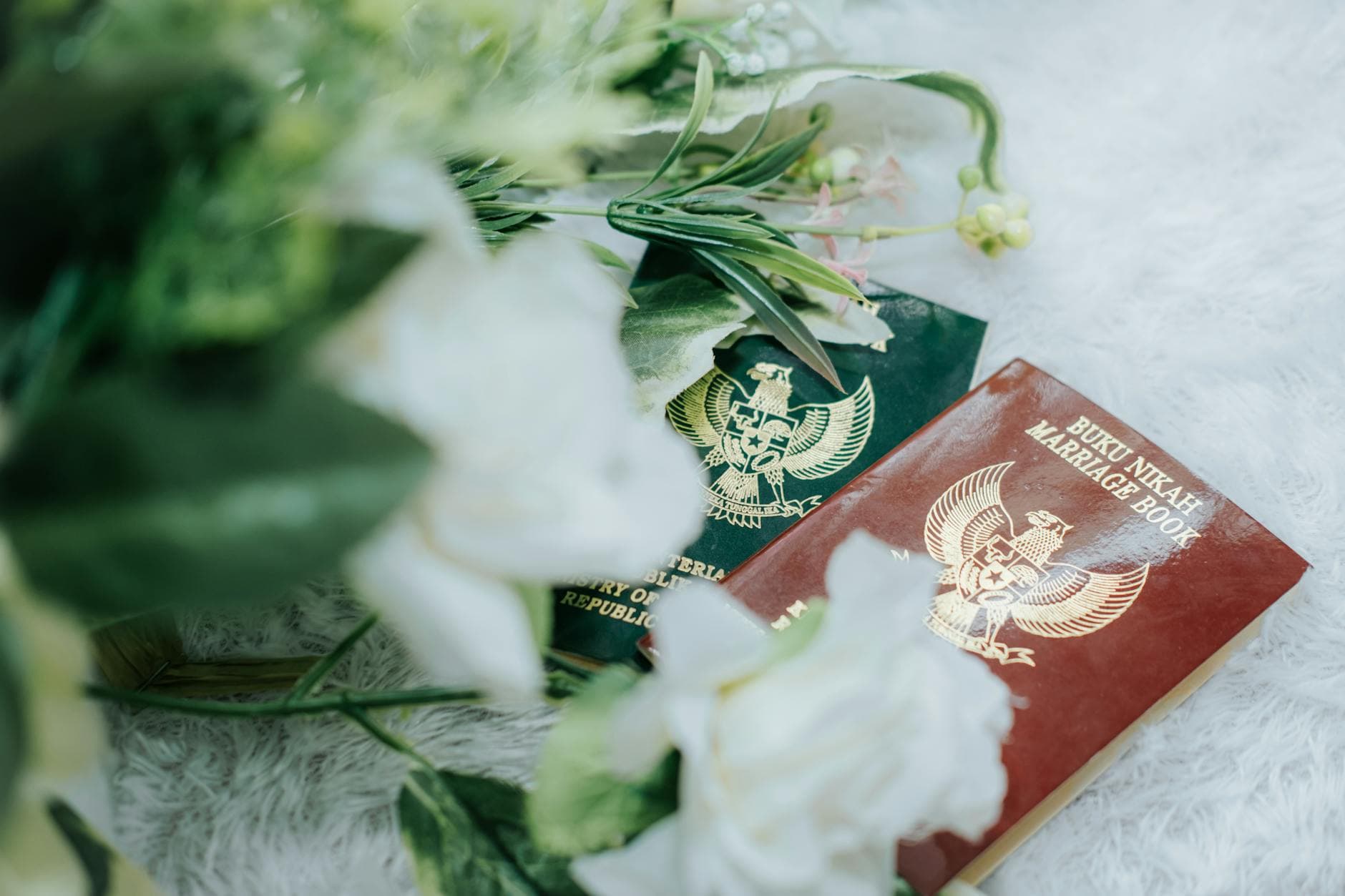 Close-up of Indonesian marriage books surrounded by a floral arrangement on a soft surface. - biblical marriage advice