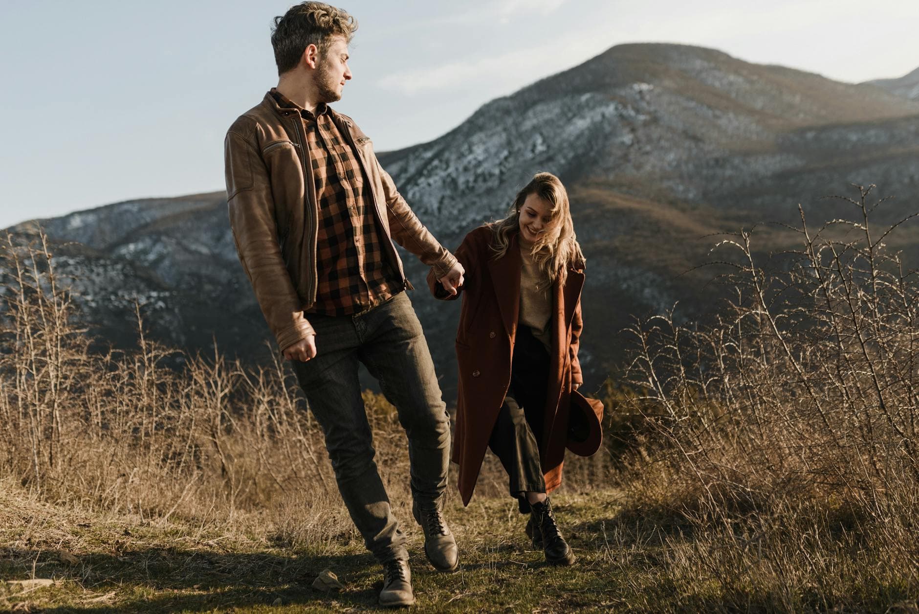 Happy couple holding hands while walking in a scenic mountain landscape, embodying love and adventure. - couple spring activities