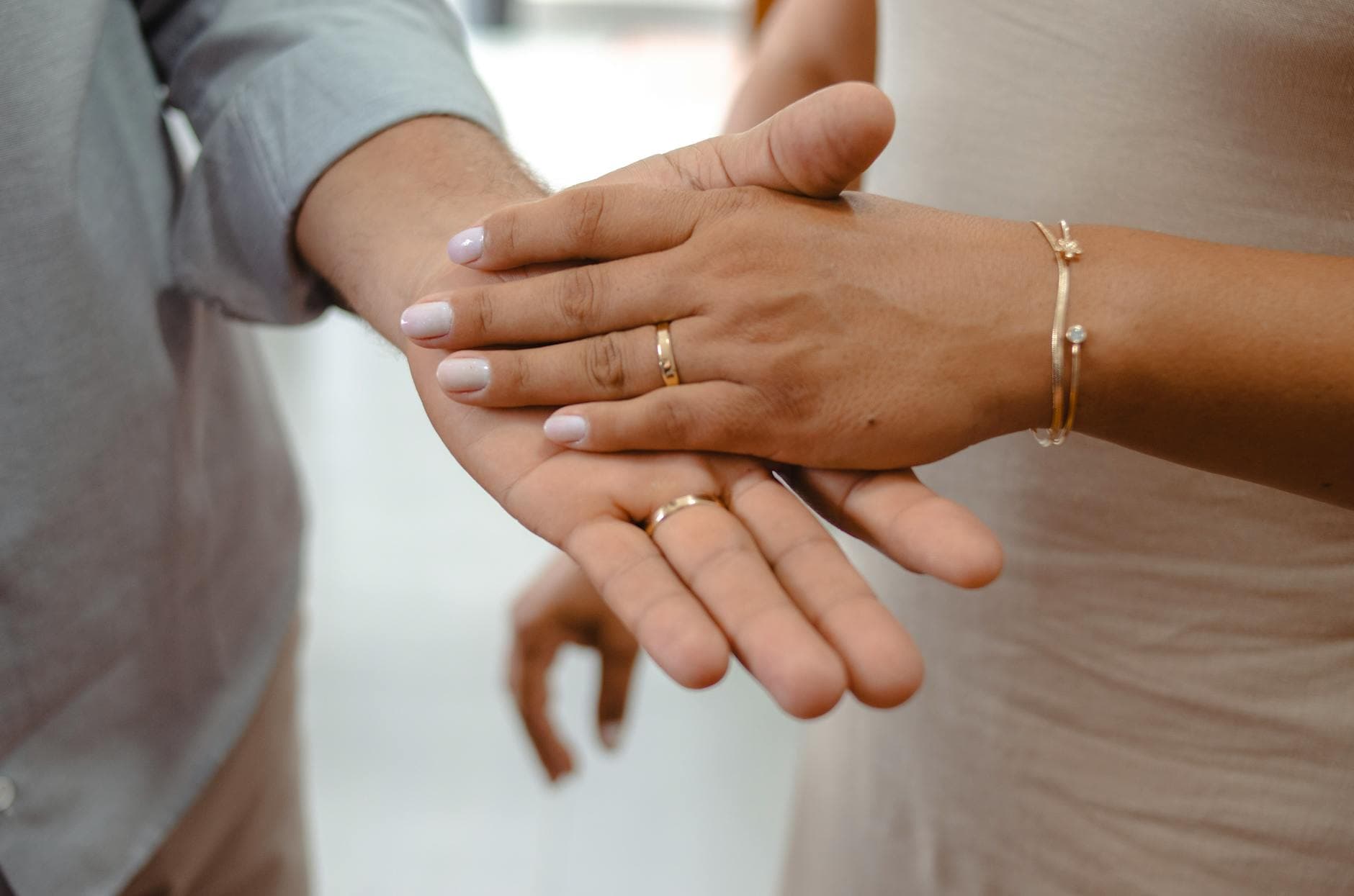 Close-up of a couple holding hands showcasing gold rings and bracelets. - couples therapy benefits