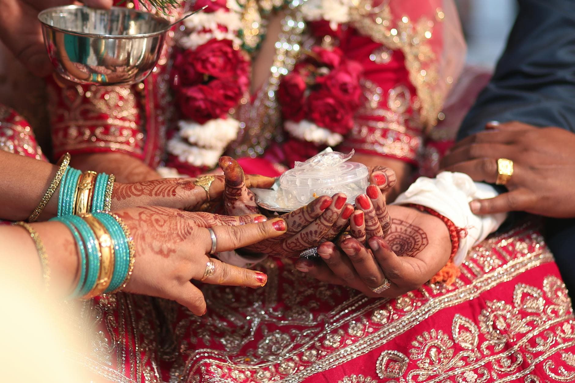 Close-up of a traditional Indian wedding ceremony featuring henna-adorned hands and colorful attire. - marriage connection rituals
