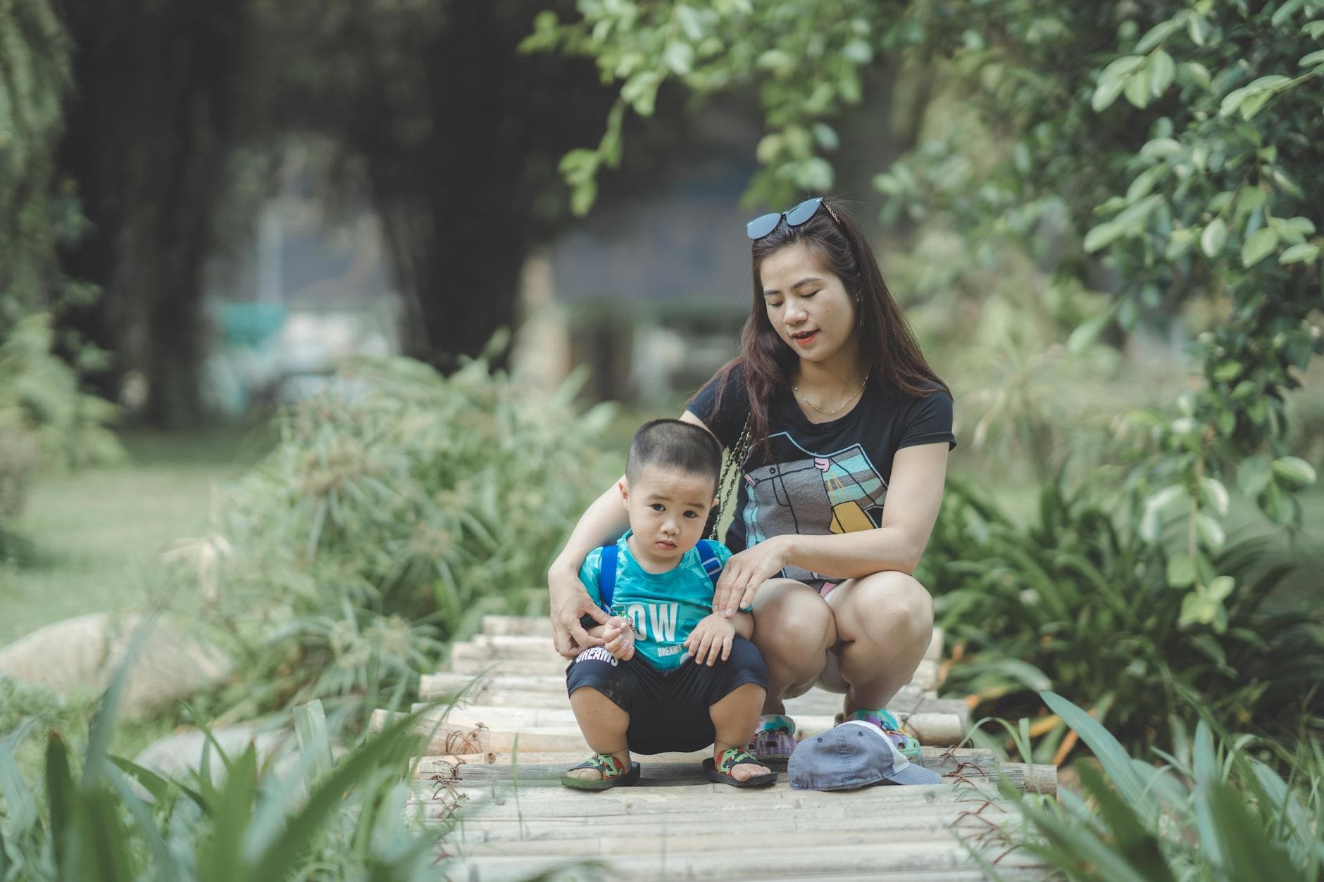 A mother and son share a joyful moment together in a lush outdoor setting. - parent stress relief