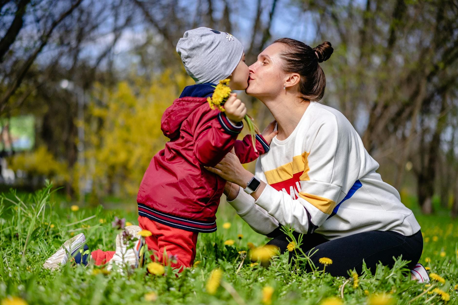 Tender moment between mother and child sharing a kiss amidst spring flowers. - parental burnout spring