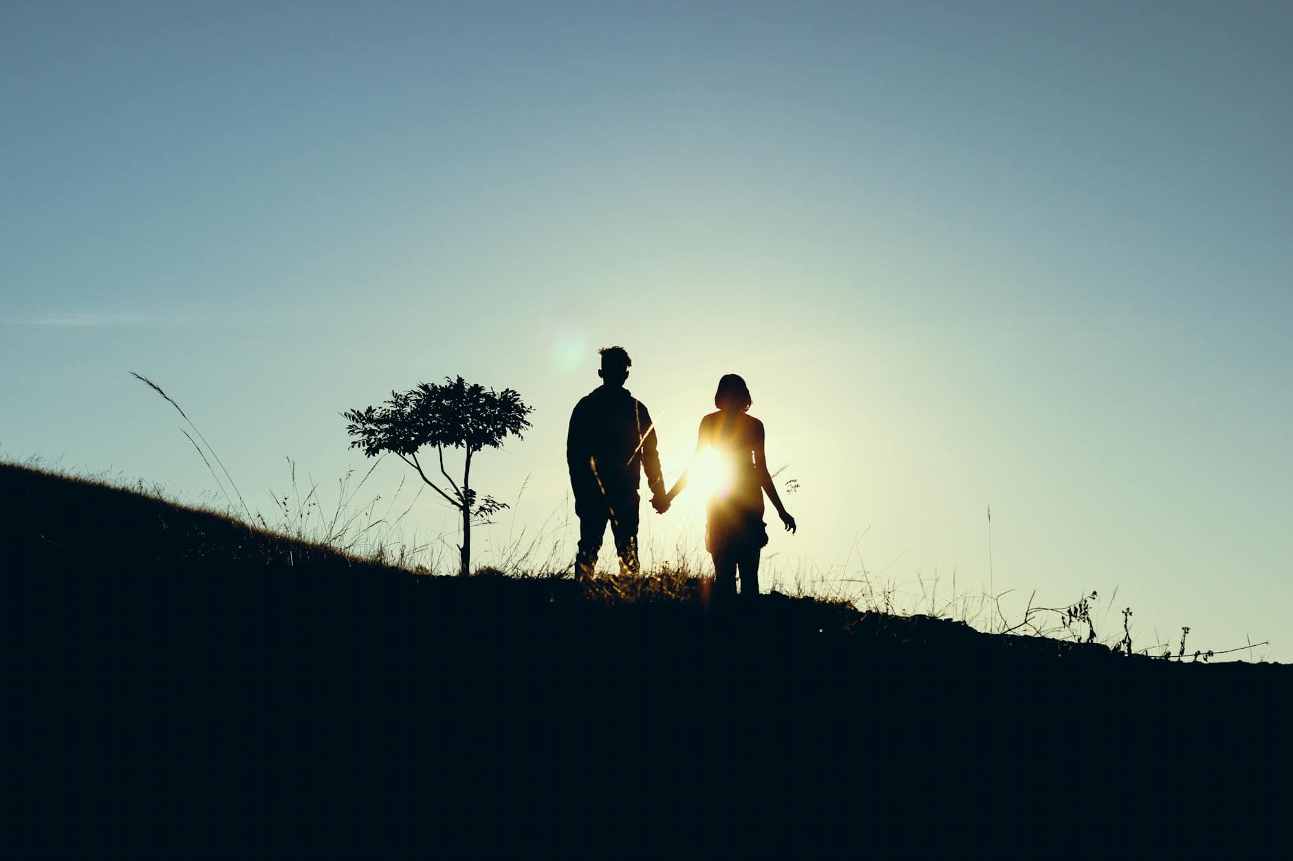 Silhouette of a couple holding hands during a serene sunset in Koraput, India. - relationship renewal therapy