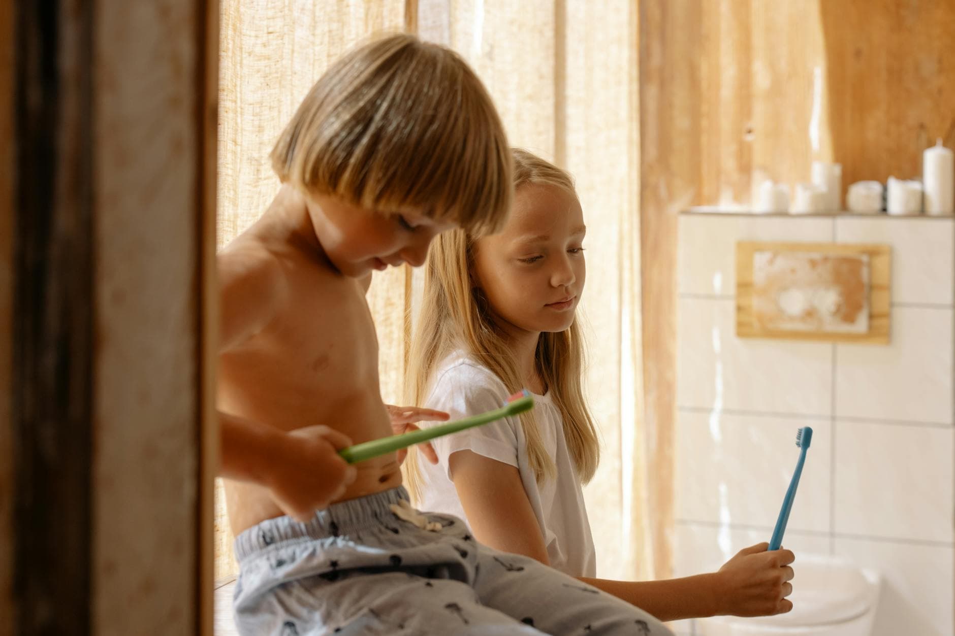 Two children brushing teeth together in a warm, sunlit bathroom promoting dental care. - sibling rivalry causes
