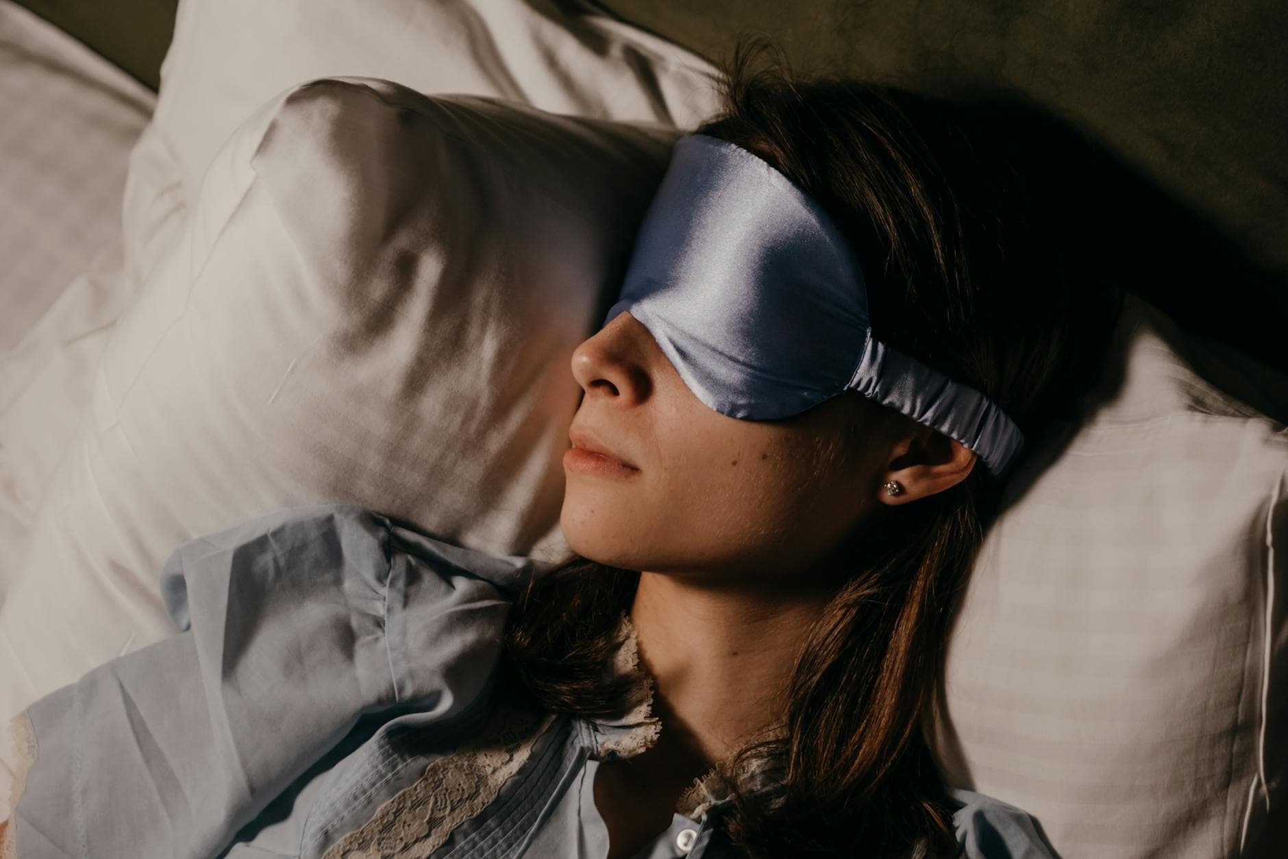 A woman peacefully sleeping indoors wearing a silk eye mask, capturing calm and relaxation. - sleep hygiene tips