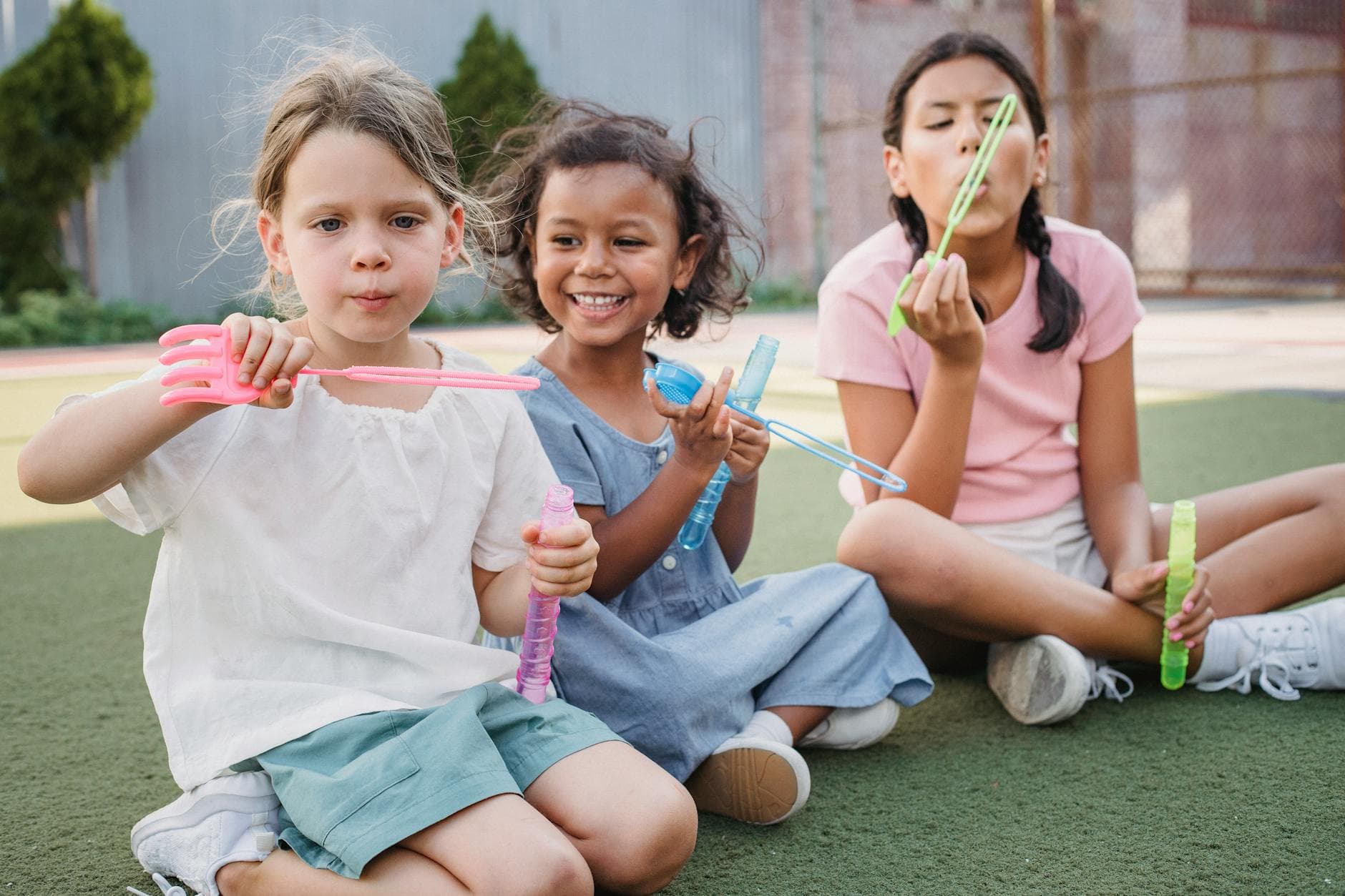 Three girls enjoying a sunny day blowing bubbles together outdoors. - social skills playdates