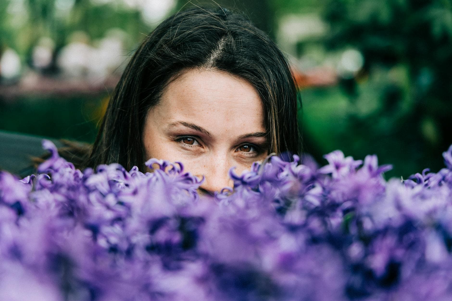 Woman peeking through vibrant purple flowers outdoors in the Netherlands. - spring allergy anxiety