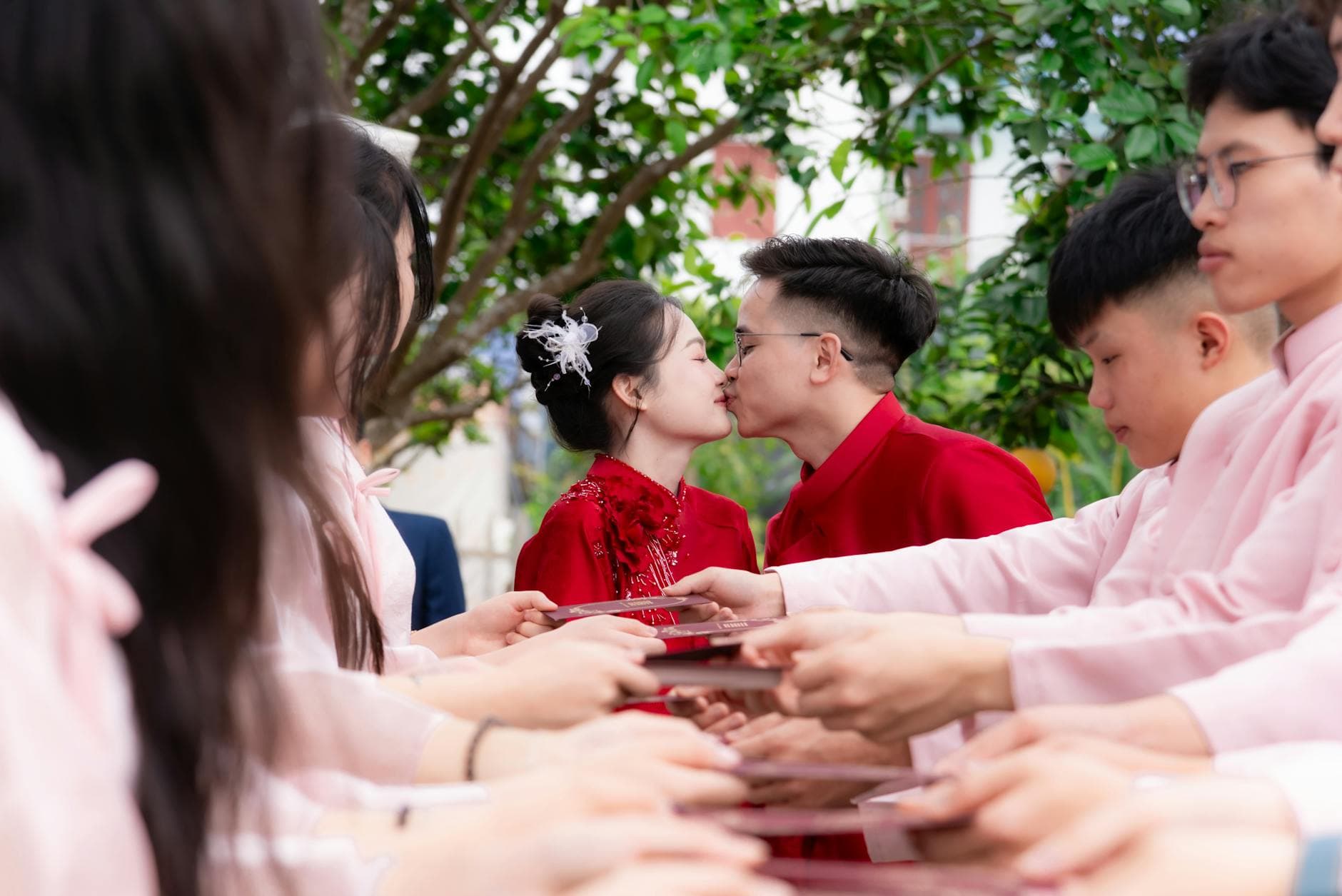 Couple kissing during festive outdoor wedding ceremony with friends. - spring marriage joy