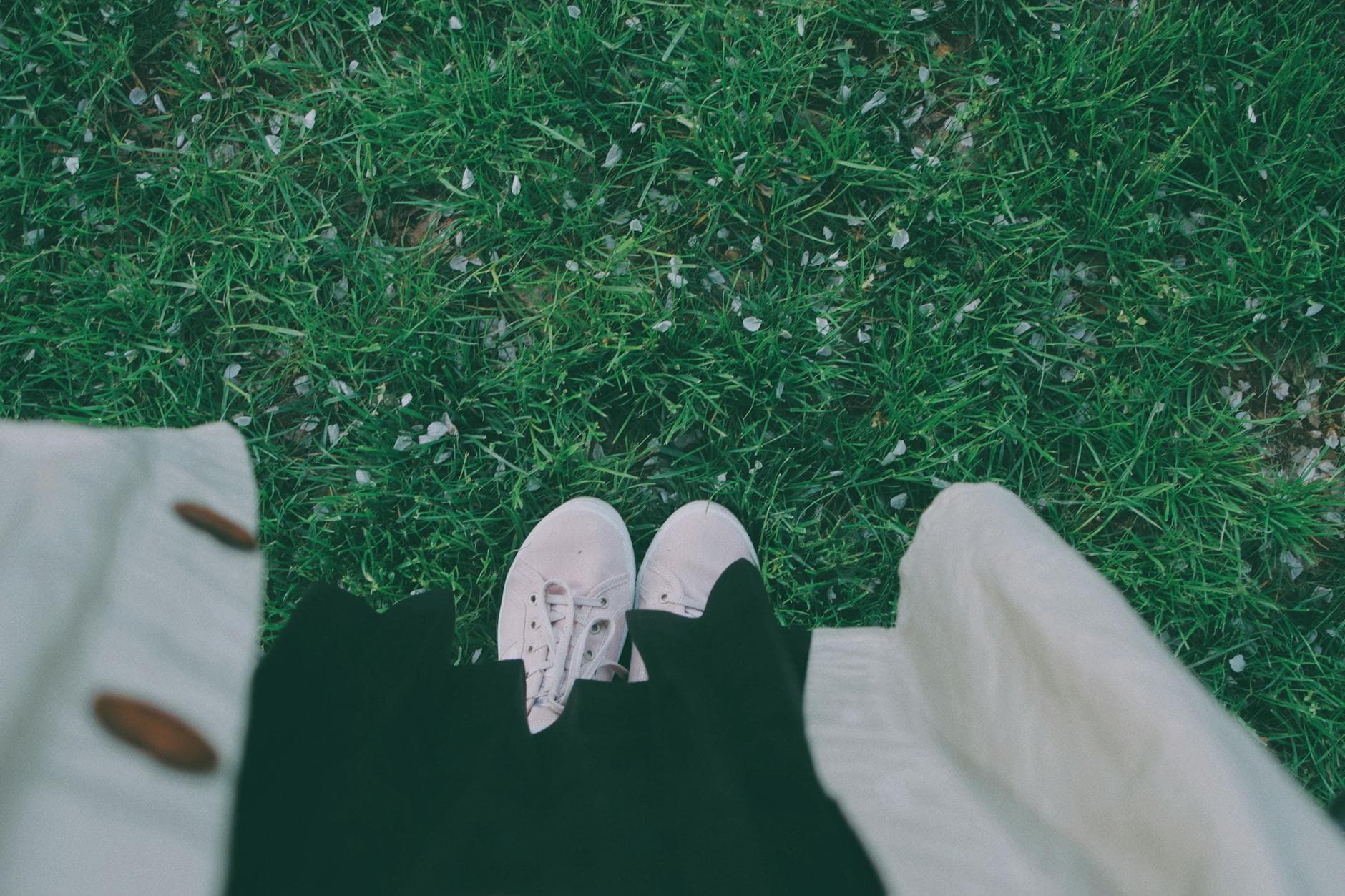 A top-down view of shoes and coat on grassy ground scattered with petals, capturing spring vibes. - spring sad coping