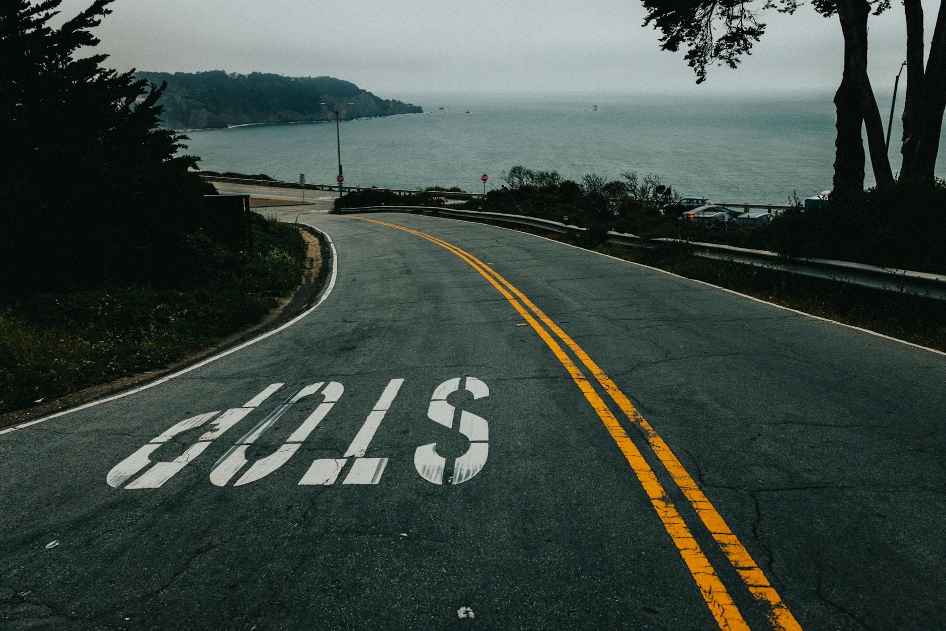 Curved road in San Francisco leading to the ocean with a clear stop sign. - stop overthinking