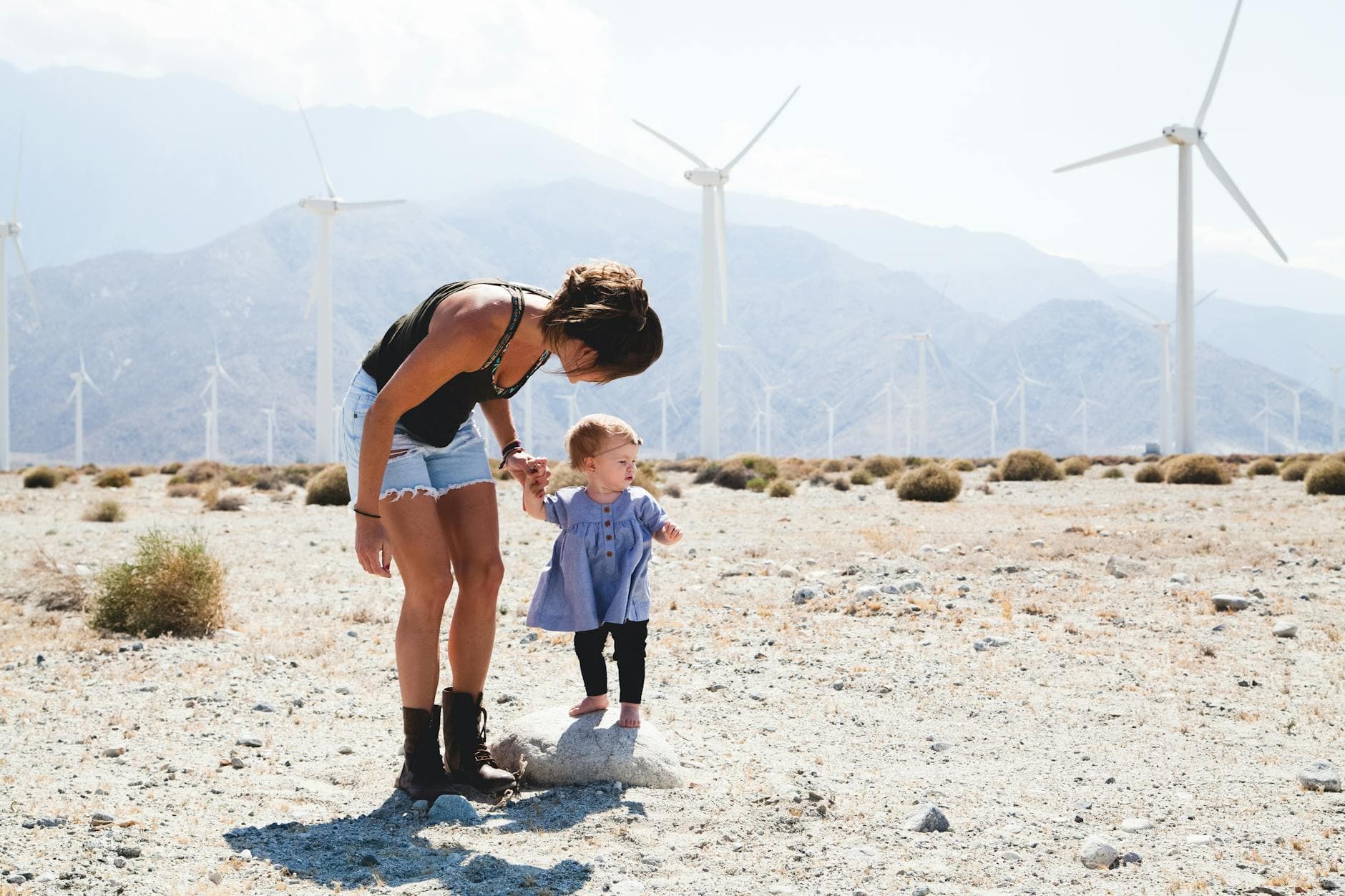 A mother and daughter exploring an outdoor wind farm, capturing a joyful, adventurous moment. - toddler energy bursts