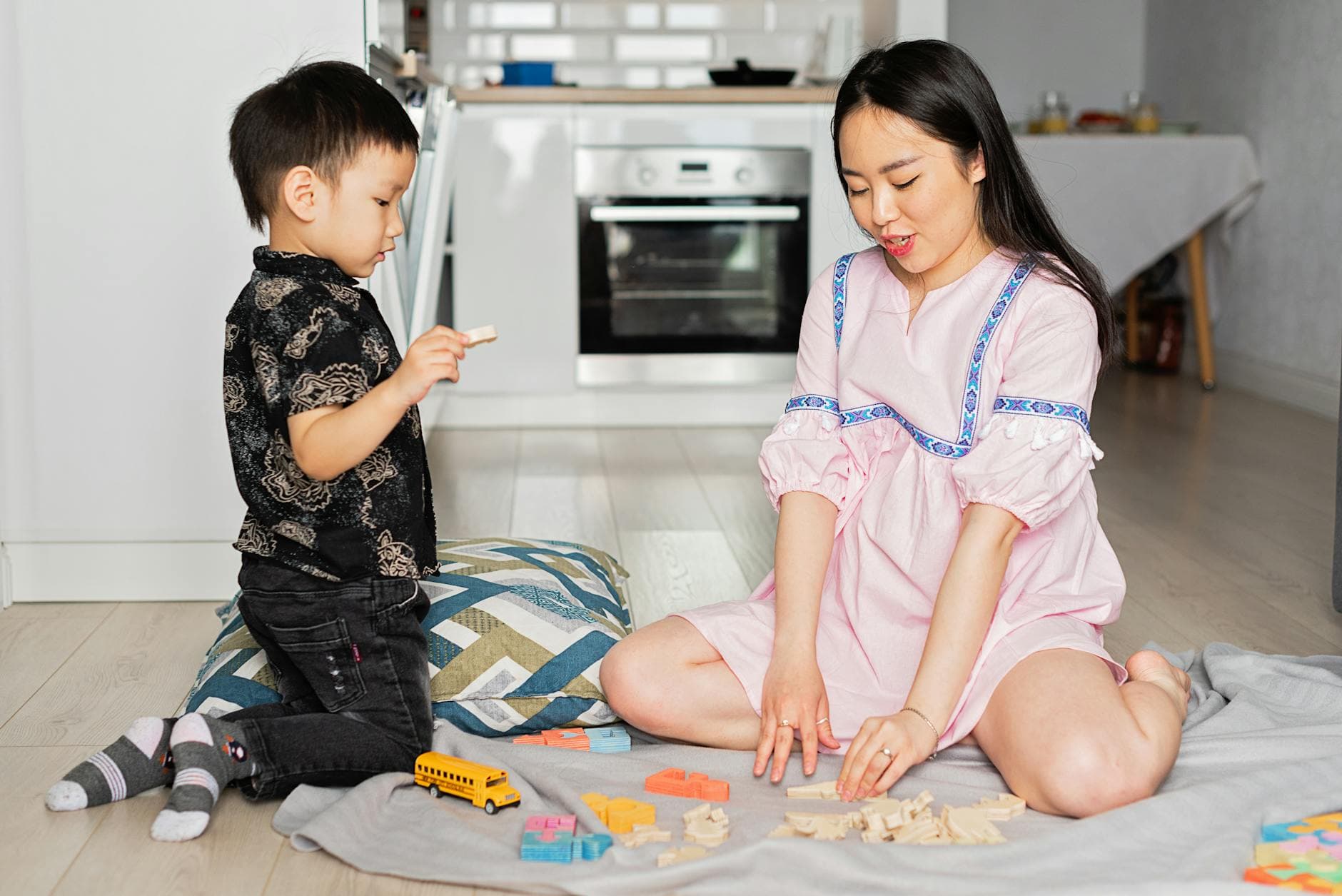Asian mother and son engaging in a playful learning activity with toys at home. - co-parenting after break
