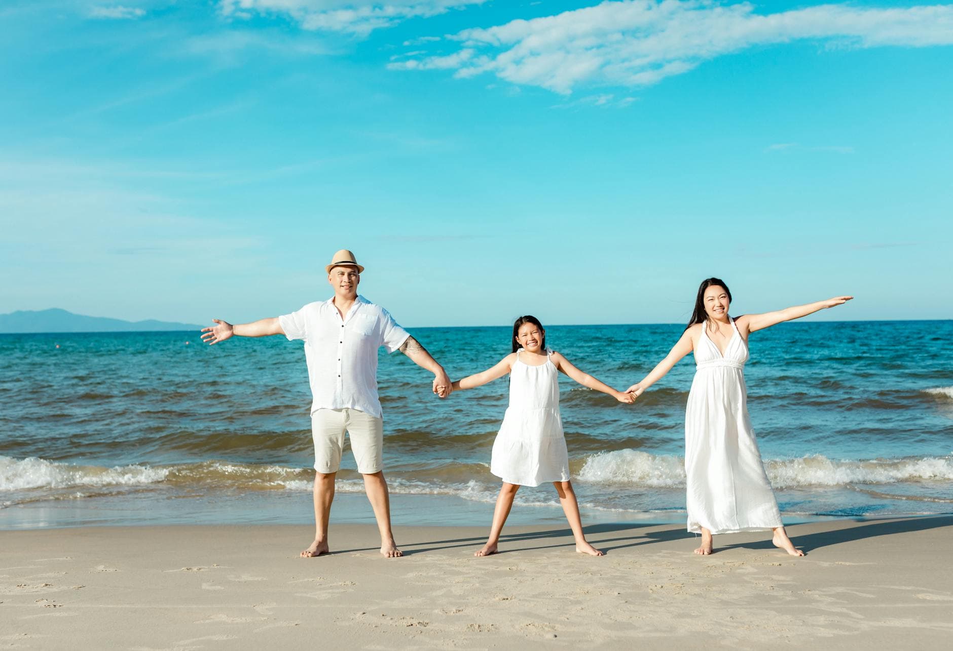 Happy family holding hands on a sunny beach in Hoi An, Vietnam. - family summer plans