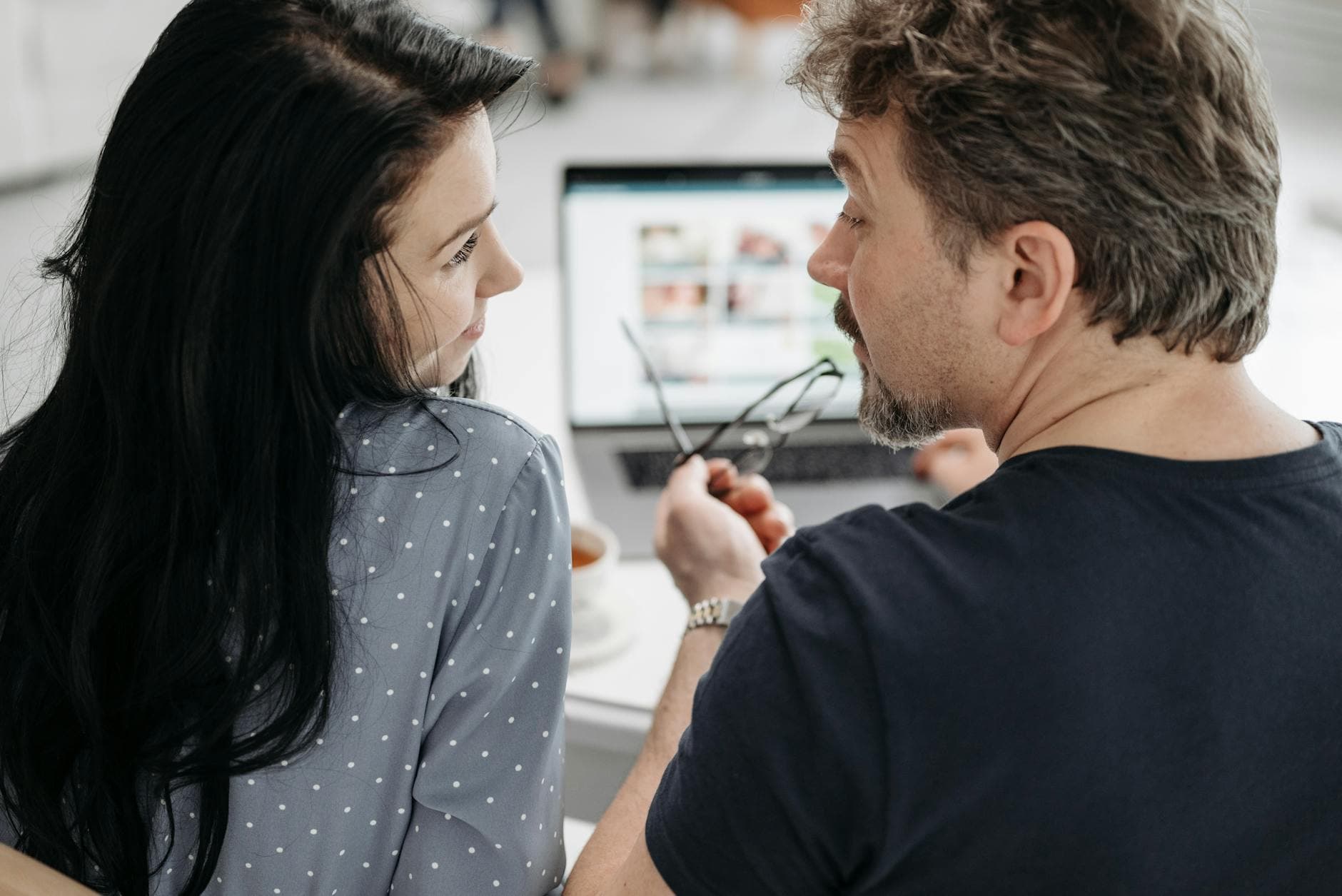 A couple having a conversation while working together on a laptop indoors. - improve relationship communication