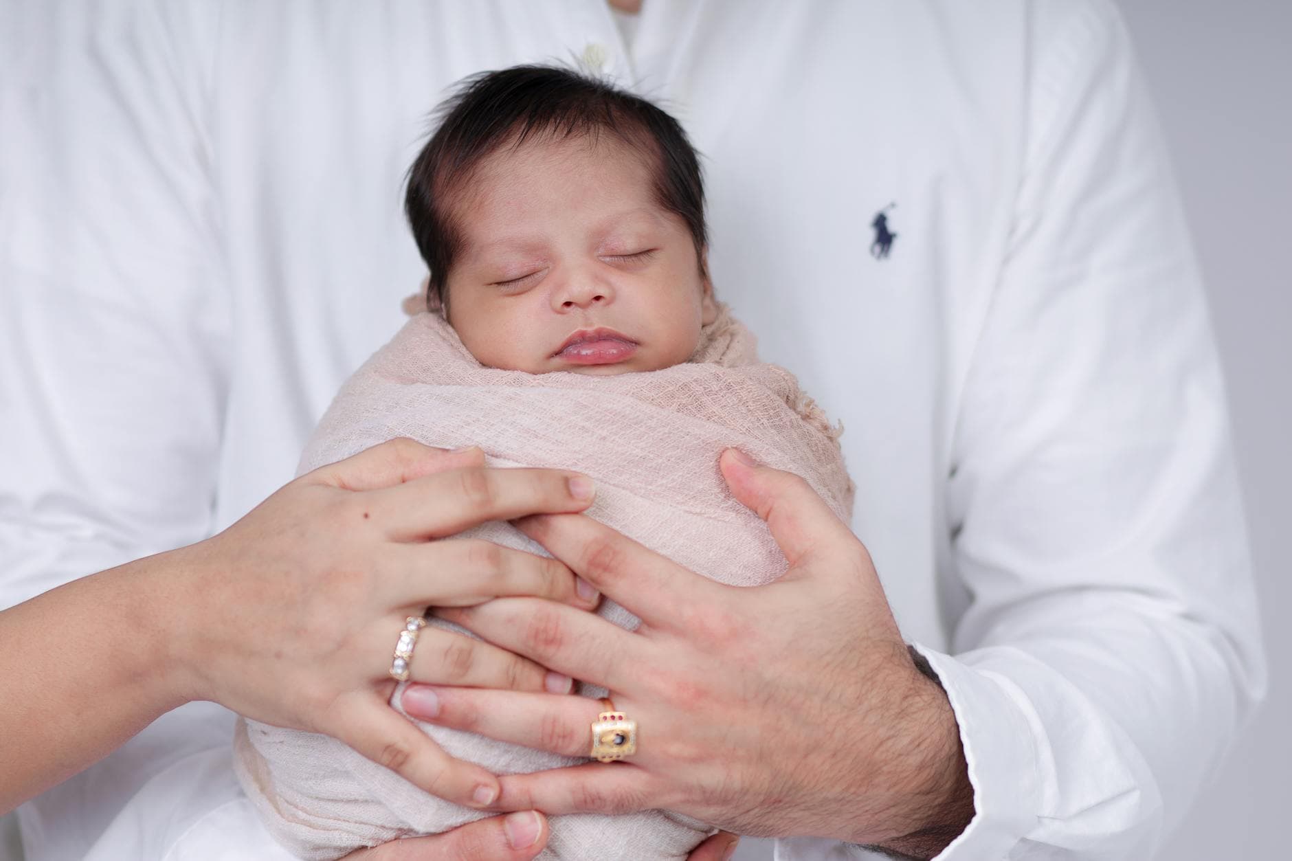 Tender moment of parents cradling their sleeping newborn, wrapped in soft cloth. - new parent sleep