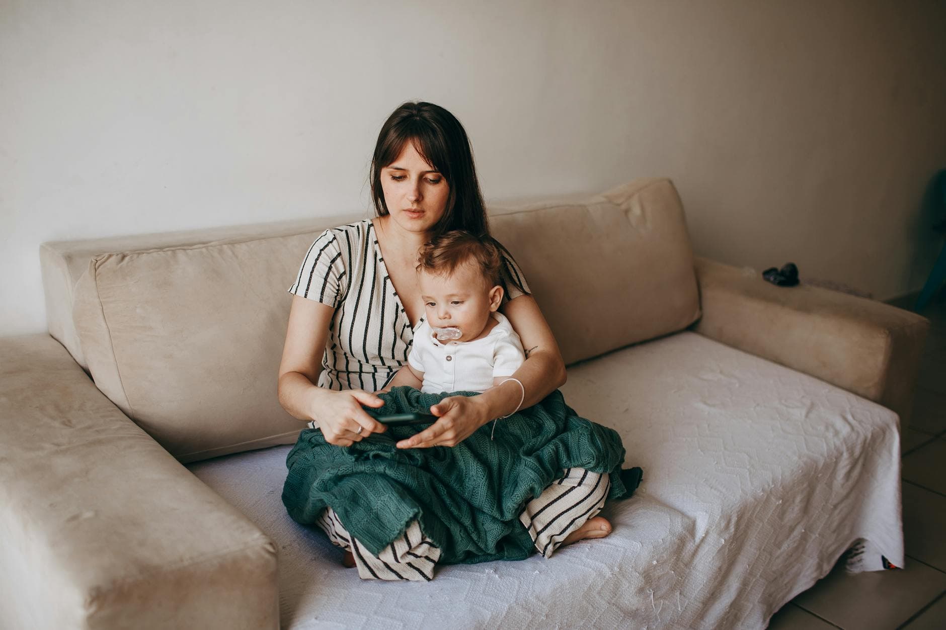 A mother and her baby seated together on a cozy sofa in a warm, loving home environment. - parental burnout self care