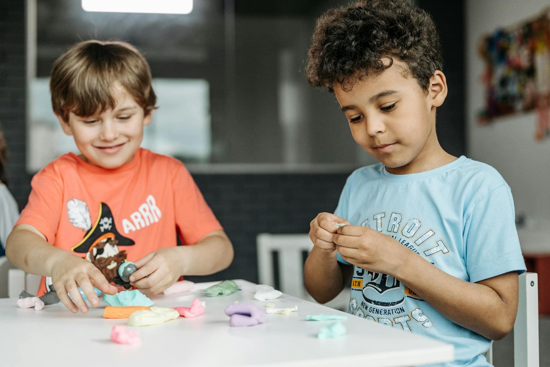 Two boys joyfully craft with clay at a table, expressing creativity indoors. - preschool spring crafts