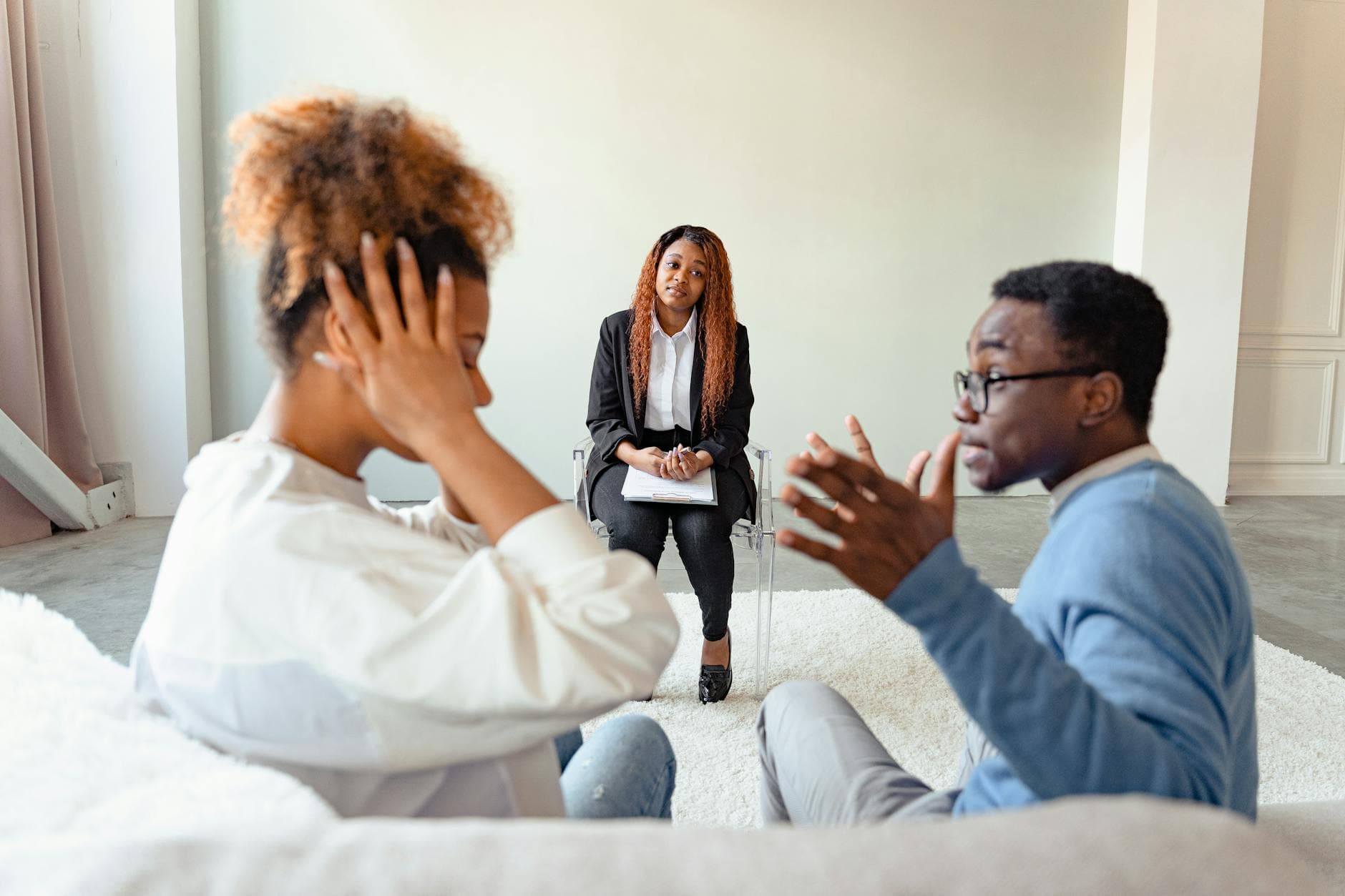 A couple in therapy session with a mental health professional indoors. - relationship boredom therapy