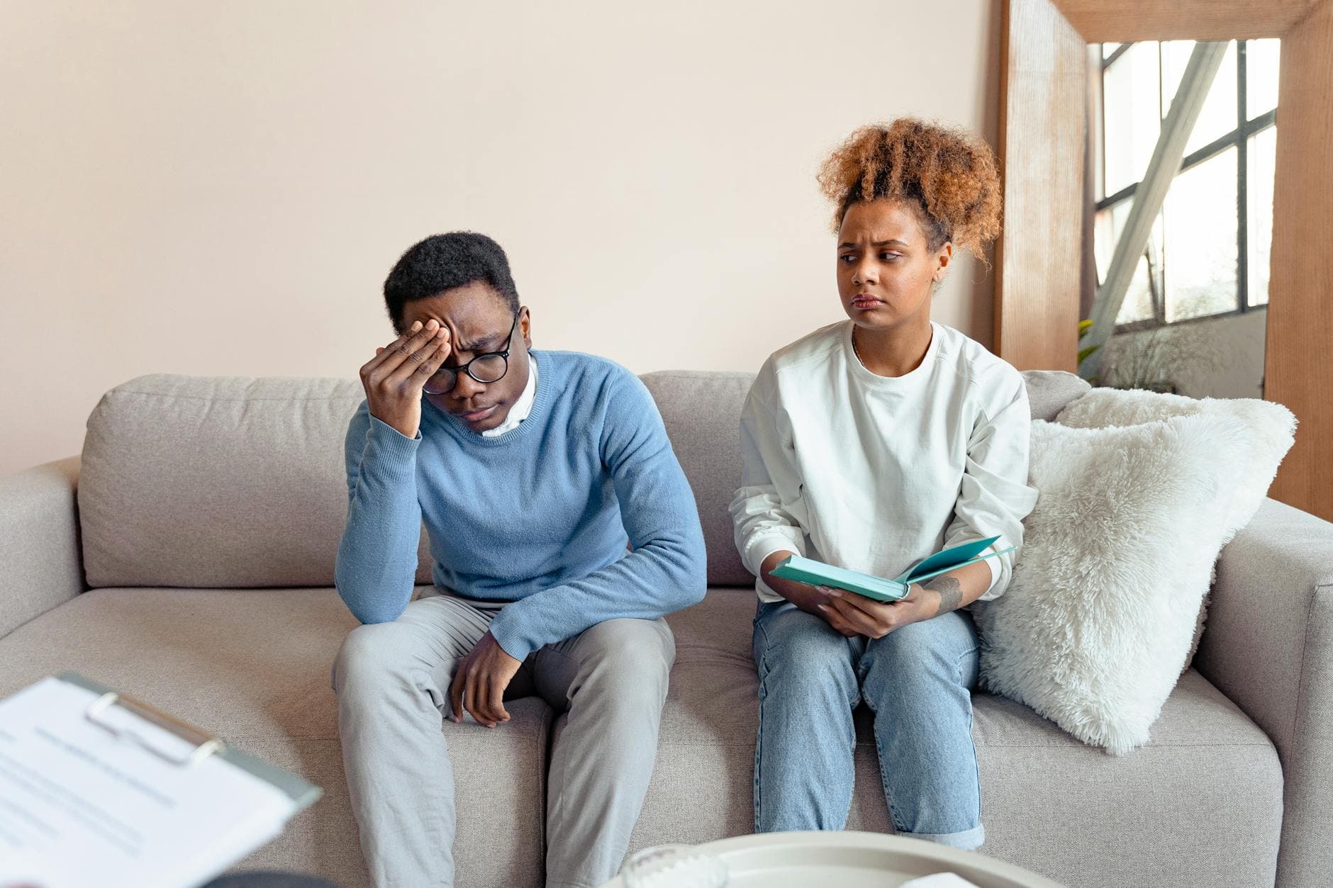 Two people sitting on a sofa indoors, engaged in a serious discussion during a therapy session. - relationship drifting therapy