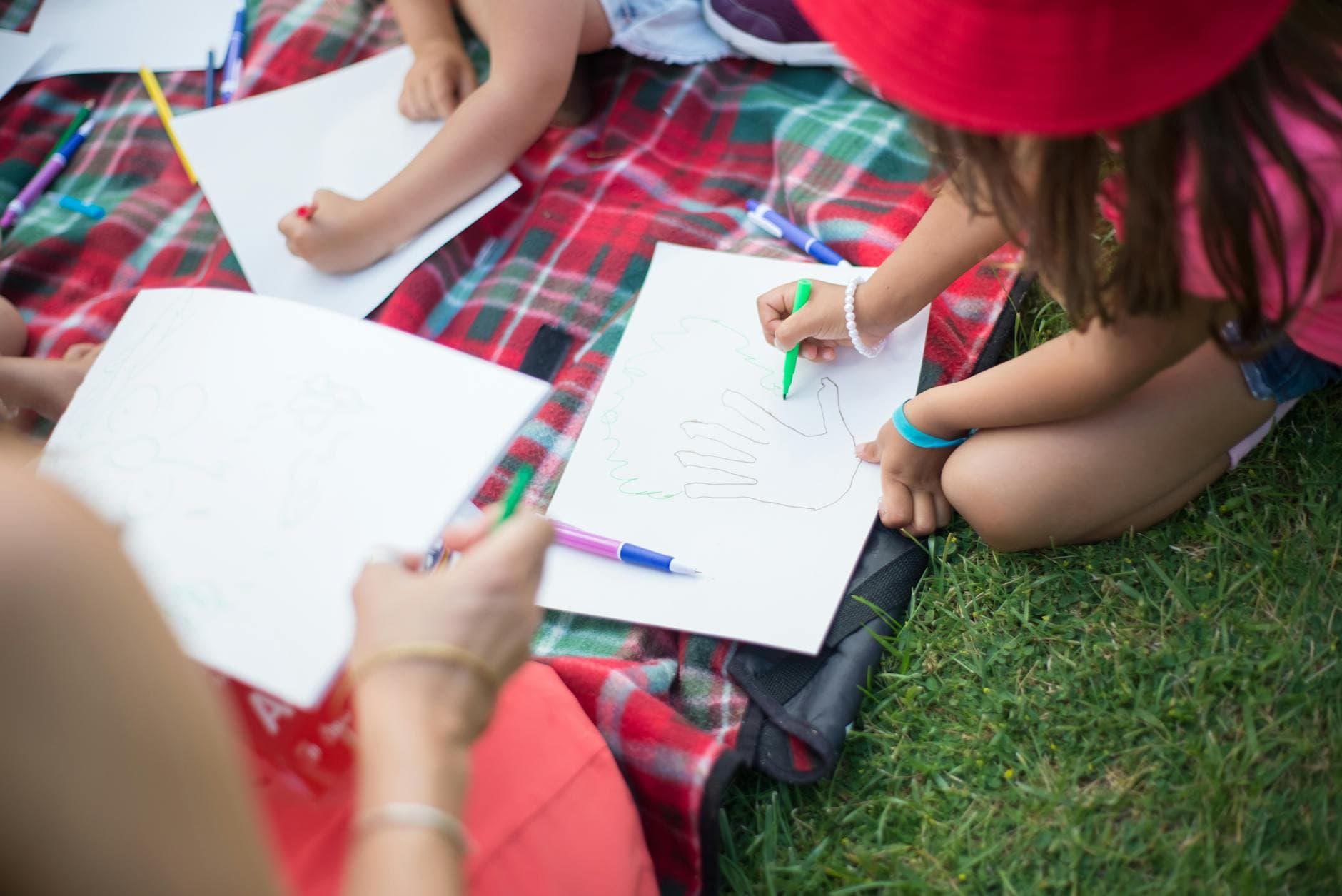 Kids engaging in creative activities on a picnic blanket outdoors during daytime in Portugal. - summer learning activities
