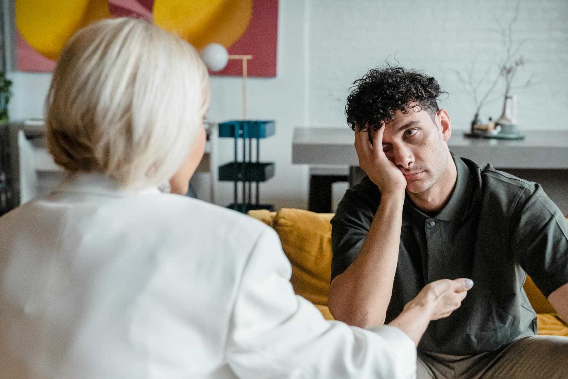 A therapist in session with a young man in a modern, artistic office setting. - therapist for relationship anxiety