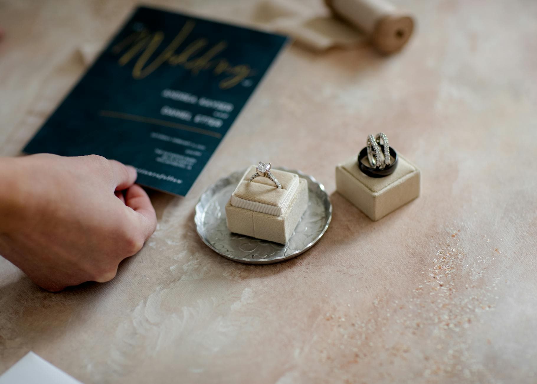 Close-up of wedding invitation and diamond rings on a tray, showcasing elegance and preparation. - wedding planning stress