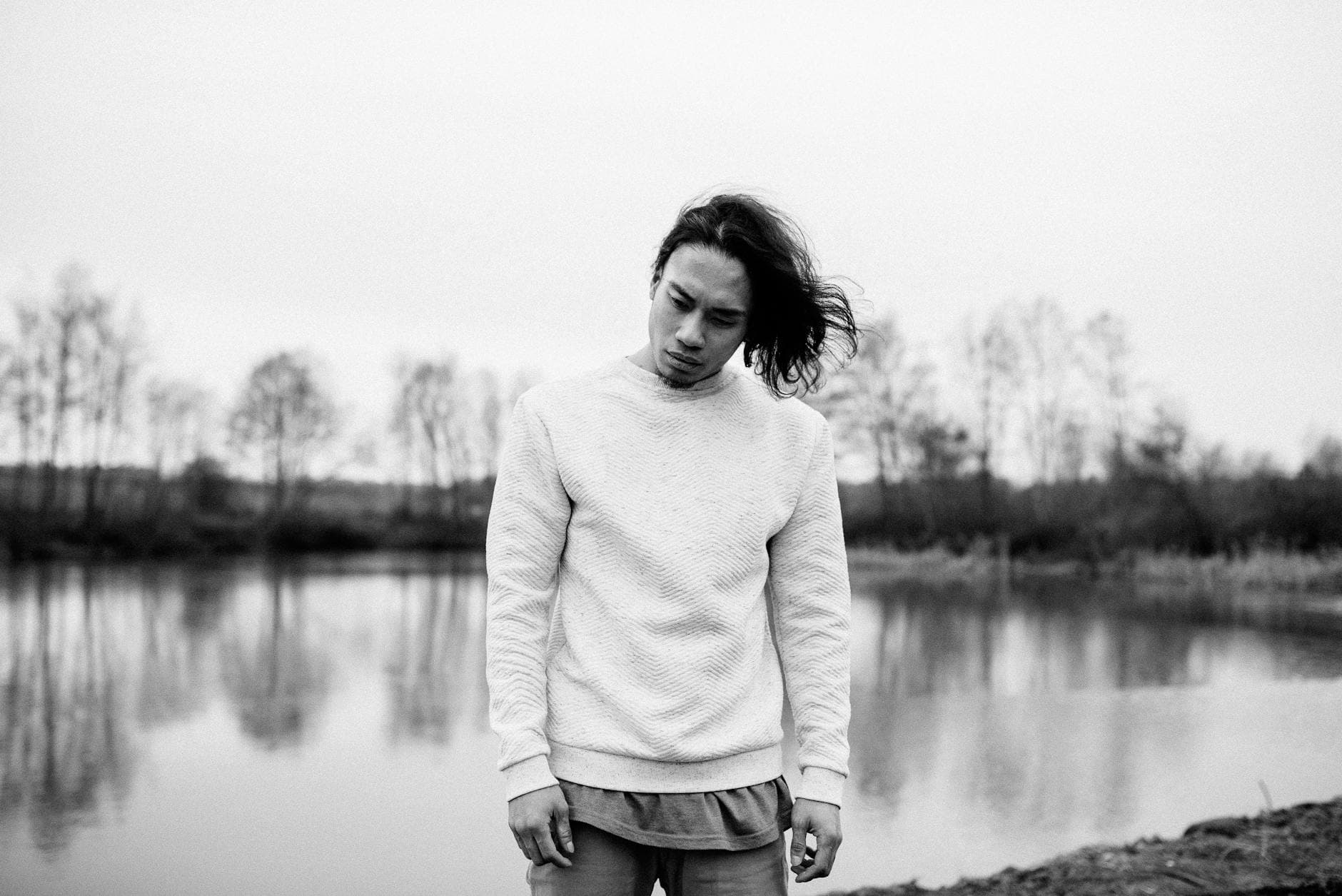 A thoughtful man stands by a serene lake, reflecting on life in a natural setting. - cbt for winter depression